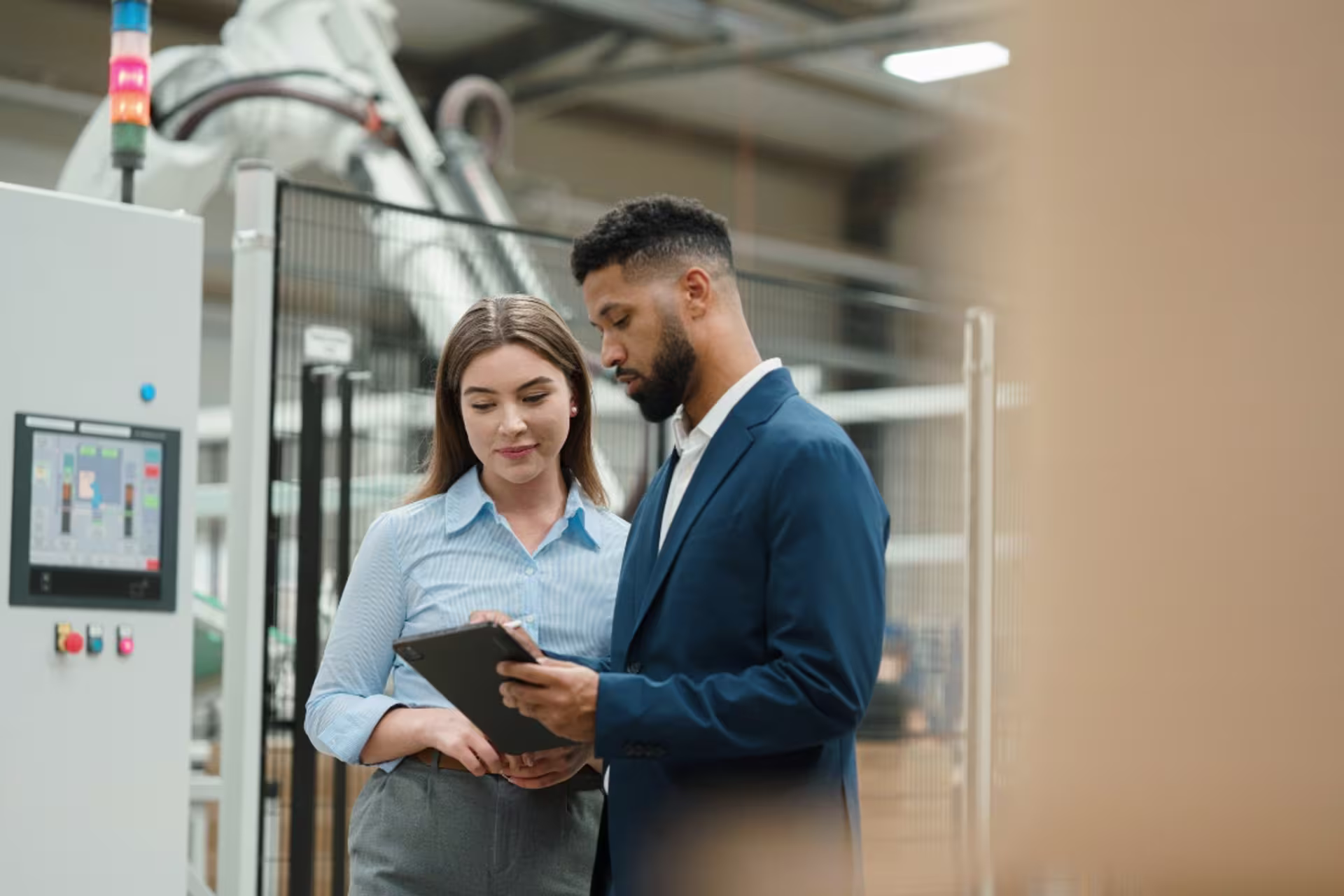 Engineering management professionals in an industrial setting, discussing operations near technical equipment.