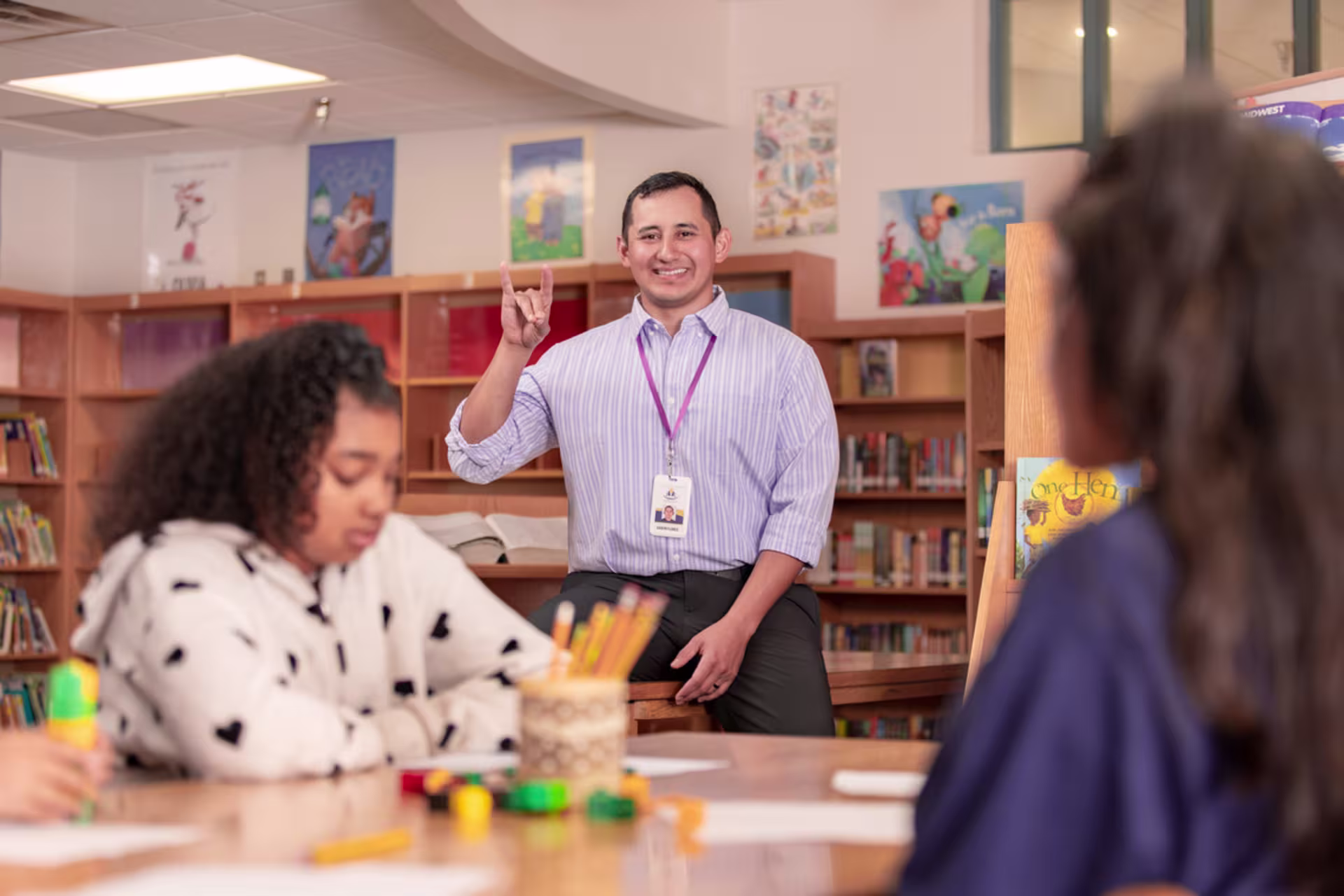 Teacher putting up lopes hand sign in classroom of elementary students.