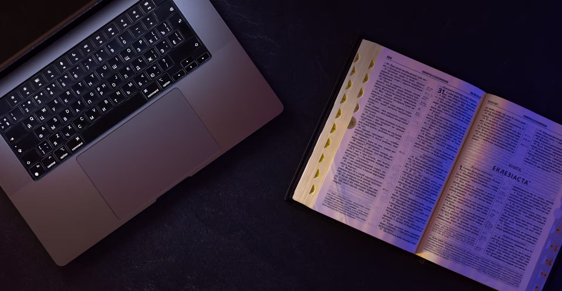 A bible open on a table with a laptop open next to it on an AI platform open on the browser, representing how AI and Christianity work together.