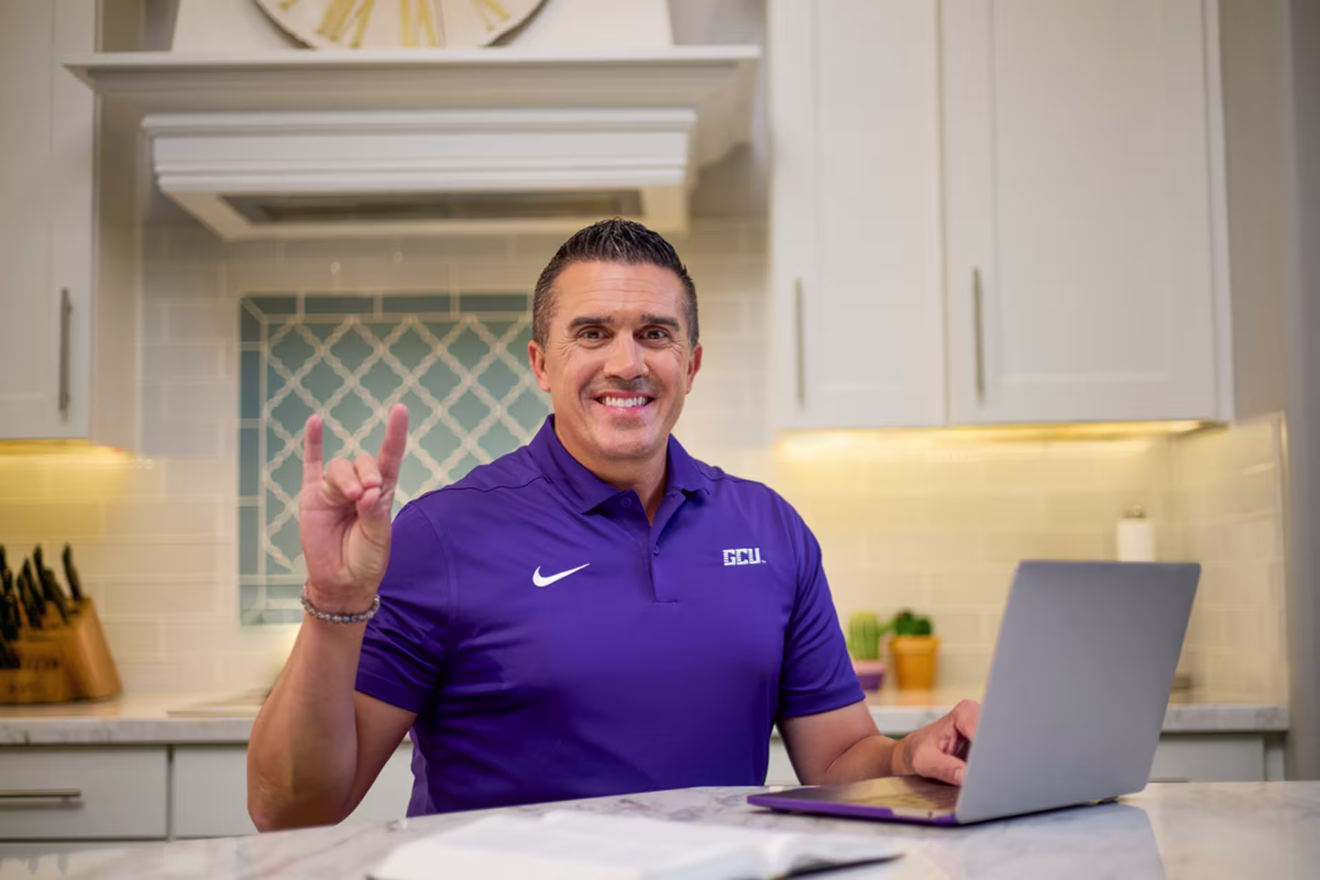 MBA student in purple polo working from home while on a laptop.