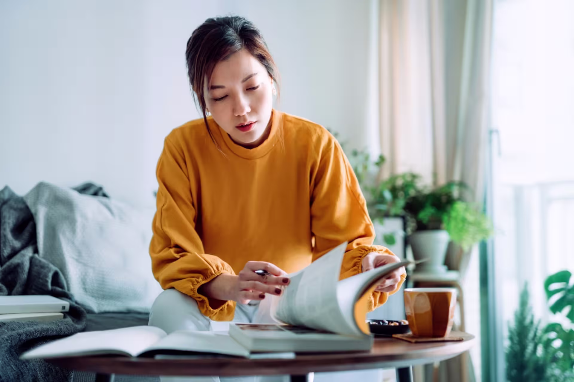 A female communications student flips through a book at a desk.
