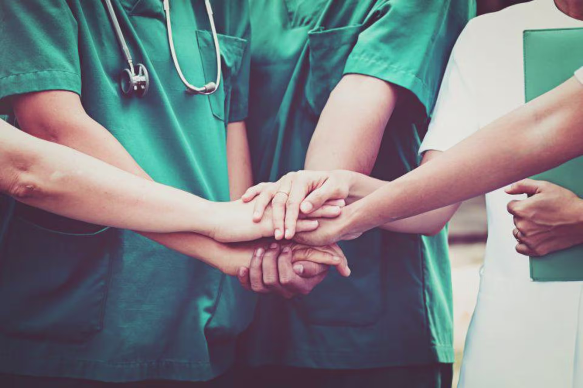 a group of nurses putting their hands together for a cheer