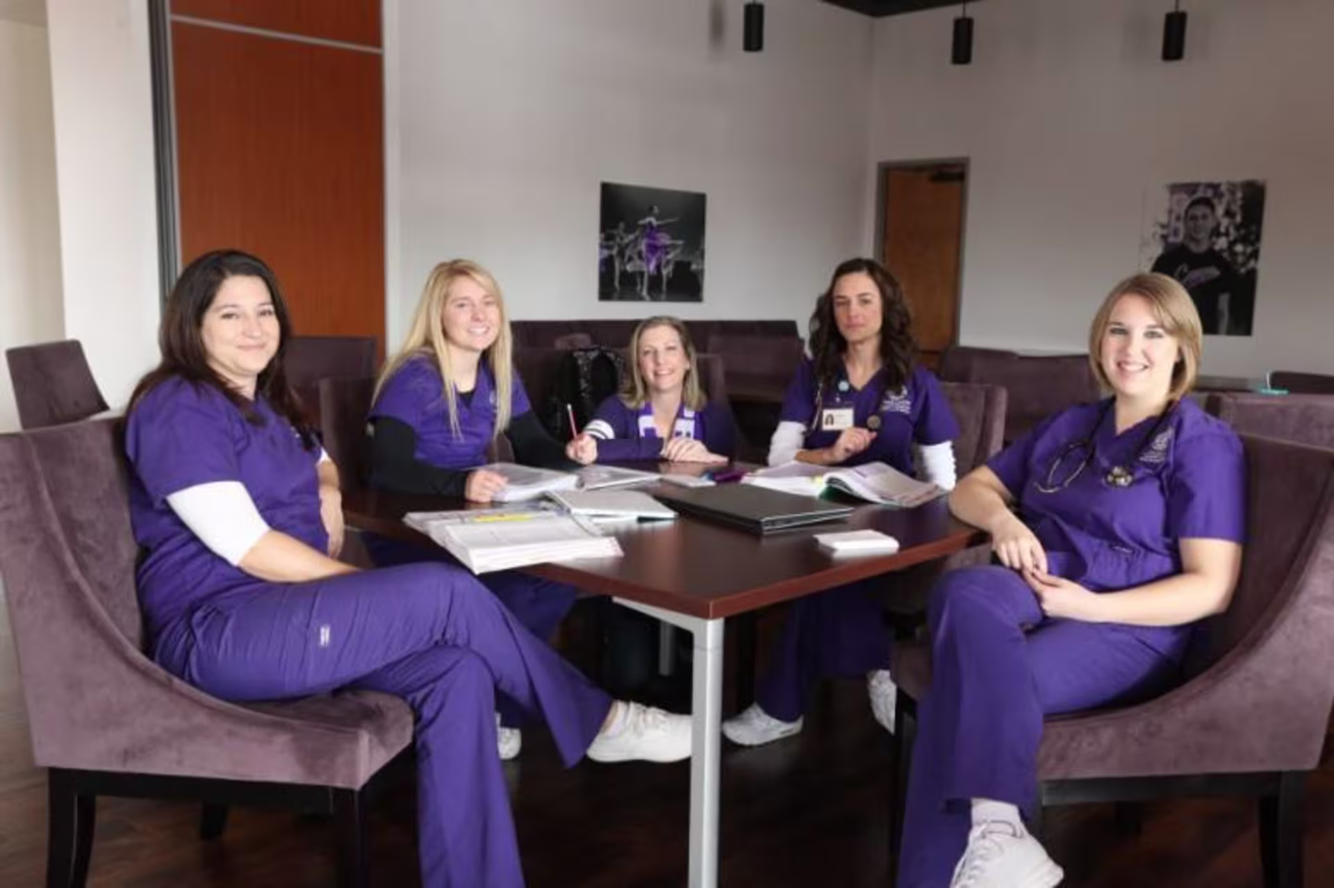 five nurses sitting around a table working