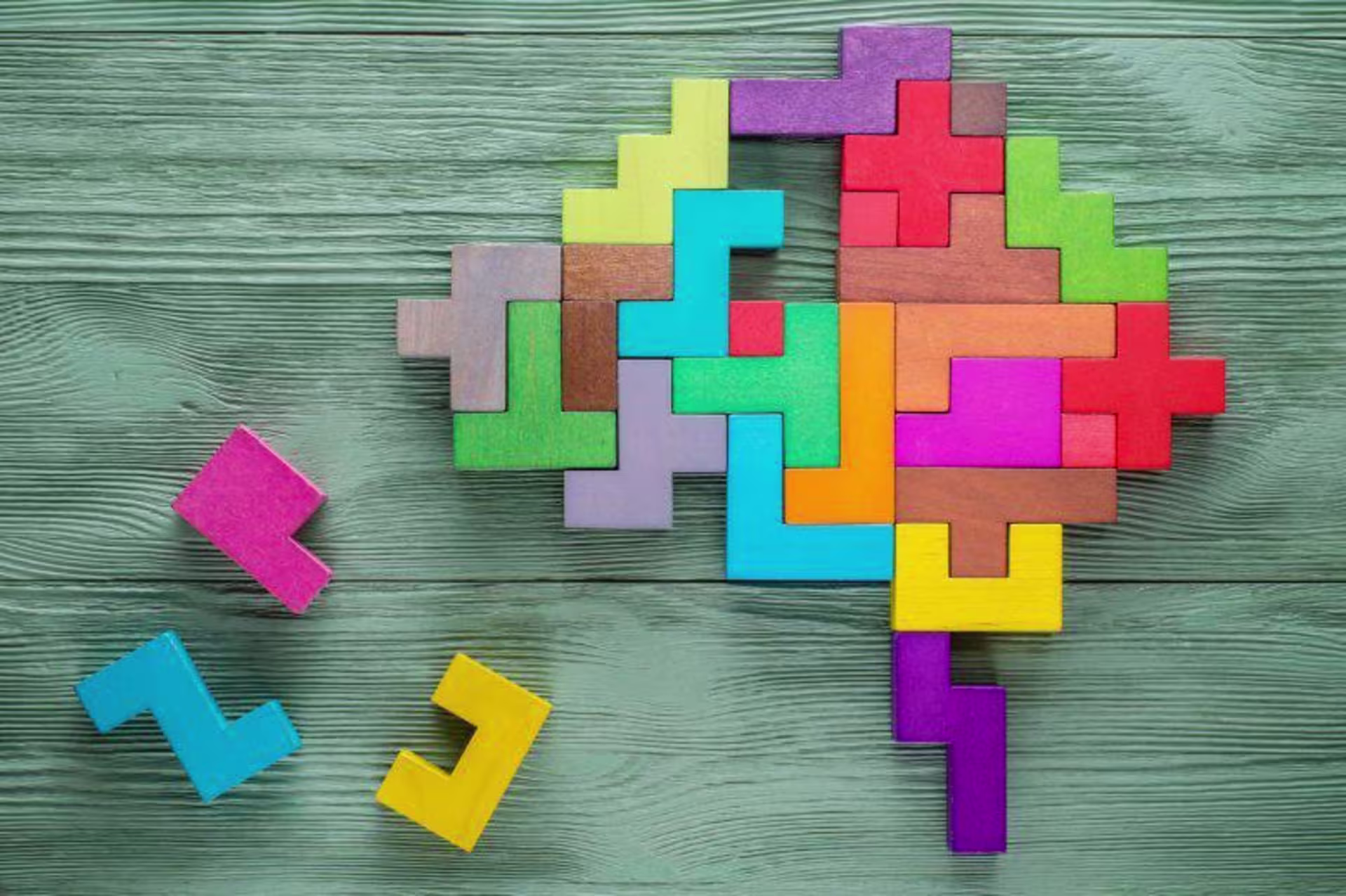 Colored puzzle pieces form a brain shape with a few missing pieces