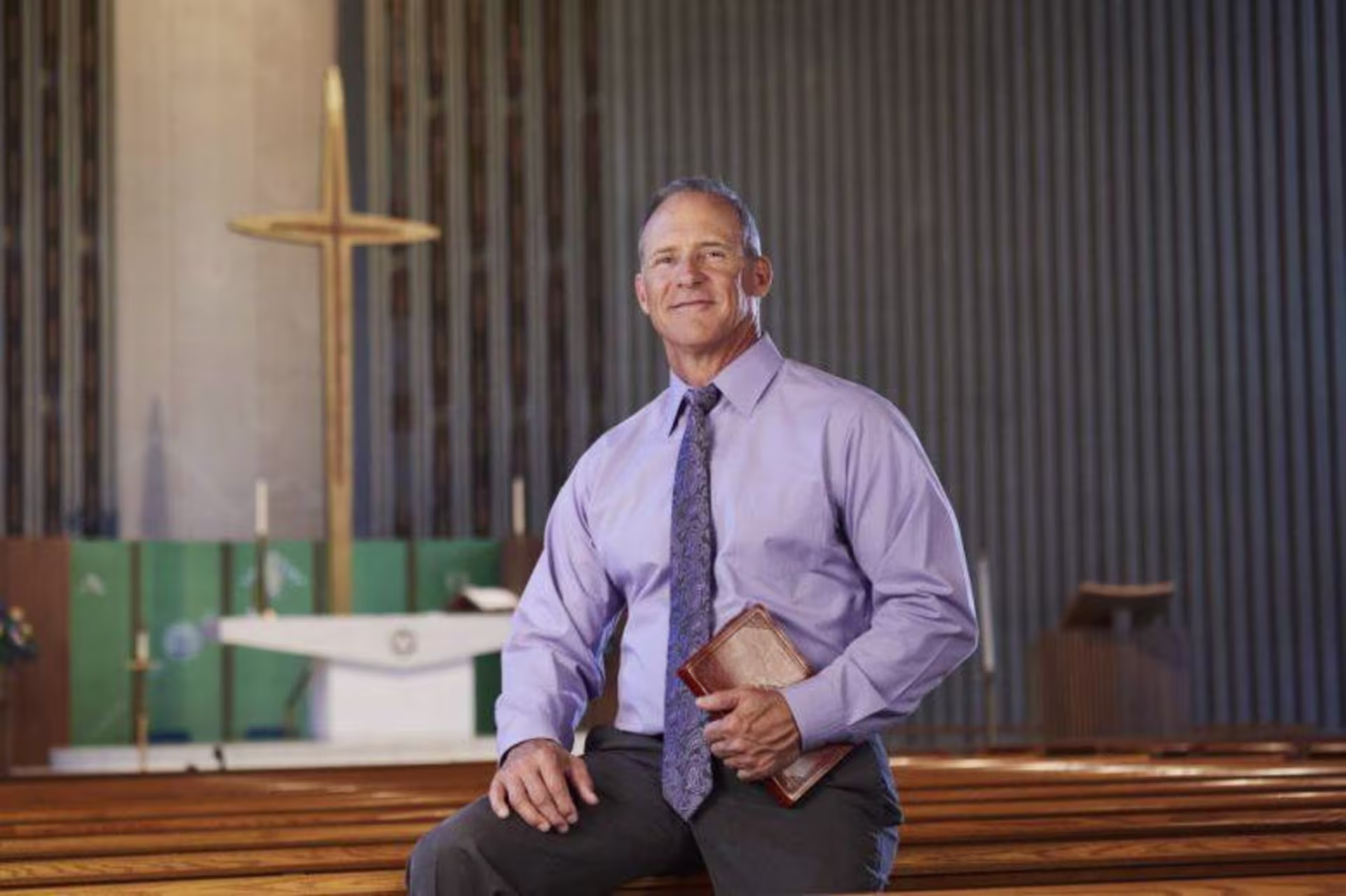 Man in a purple shirt holding a Bible