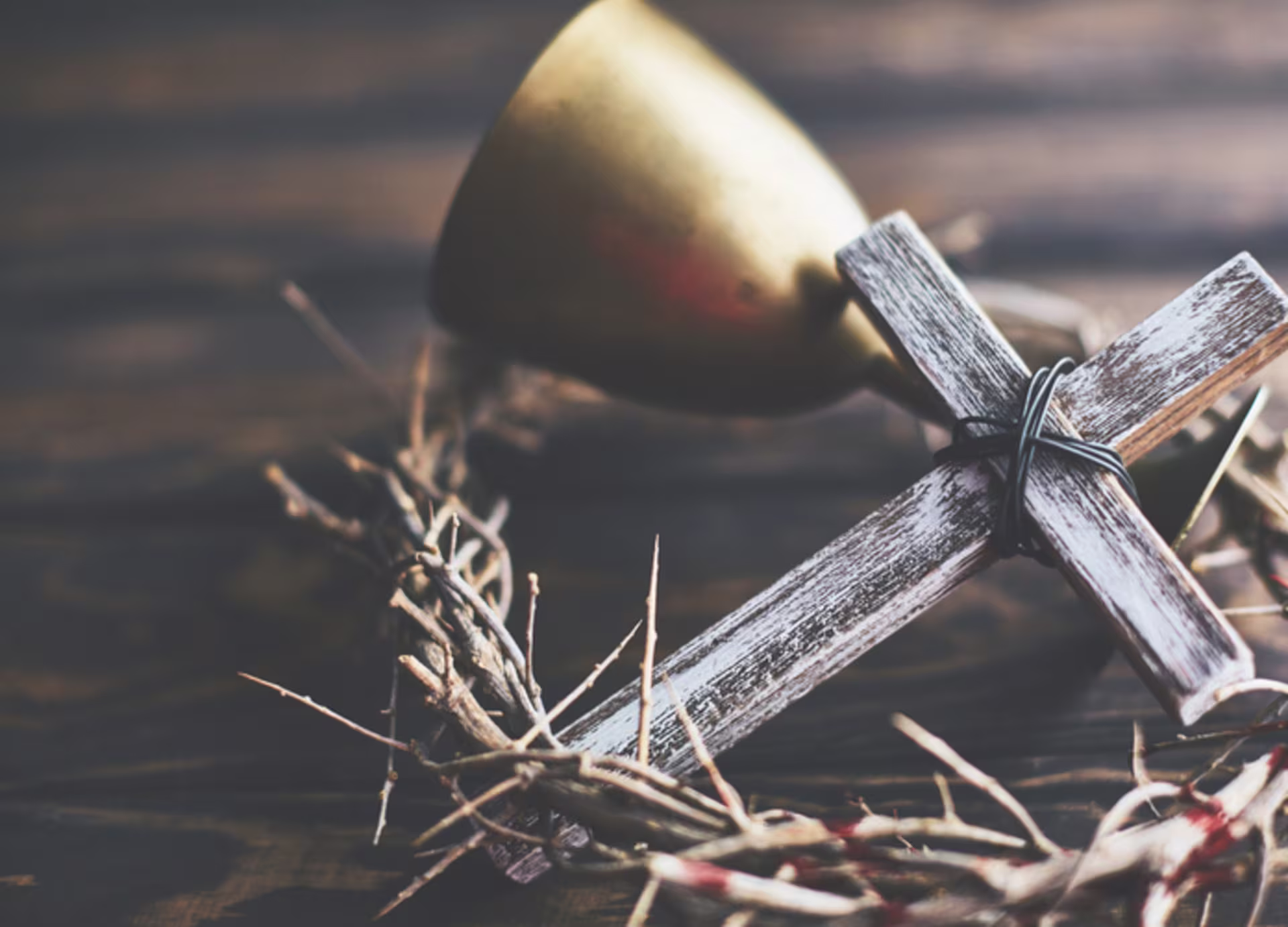 A cross lays with a crown of thorns and chalice