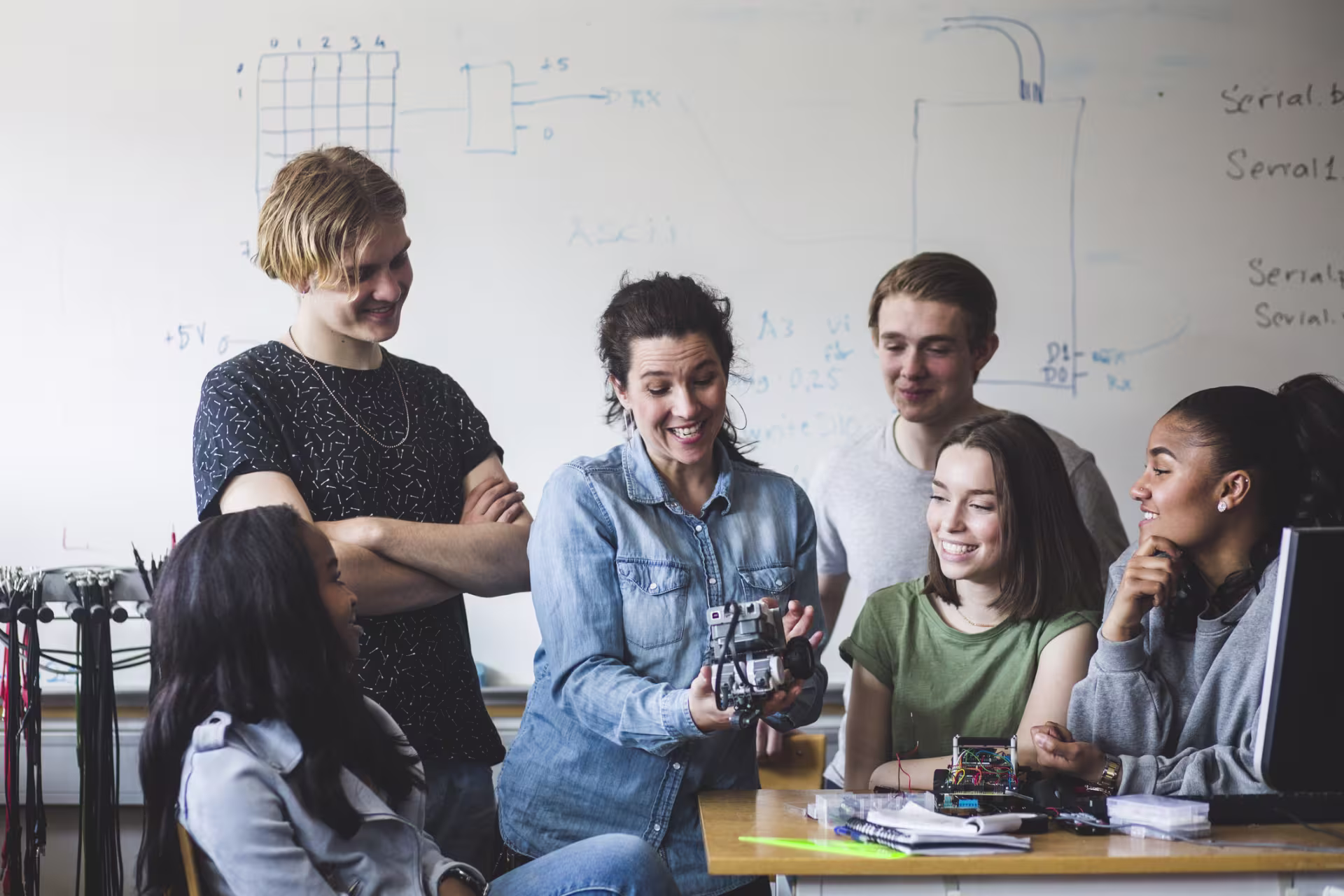 High school students working on machinery with teacher