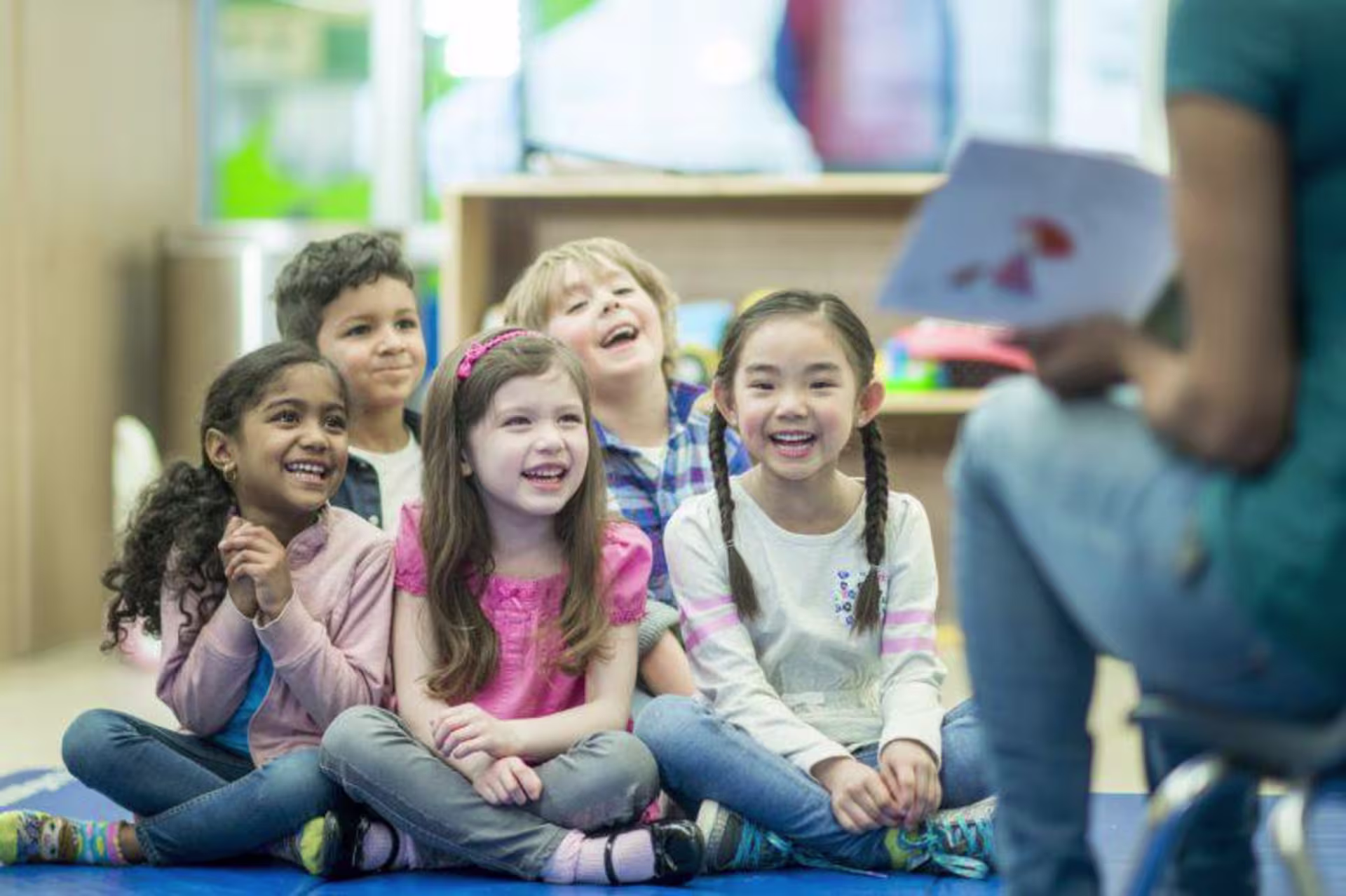 Group of kids laugh sitting on the ground during story time