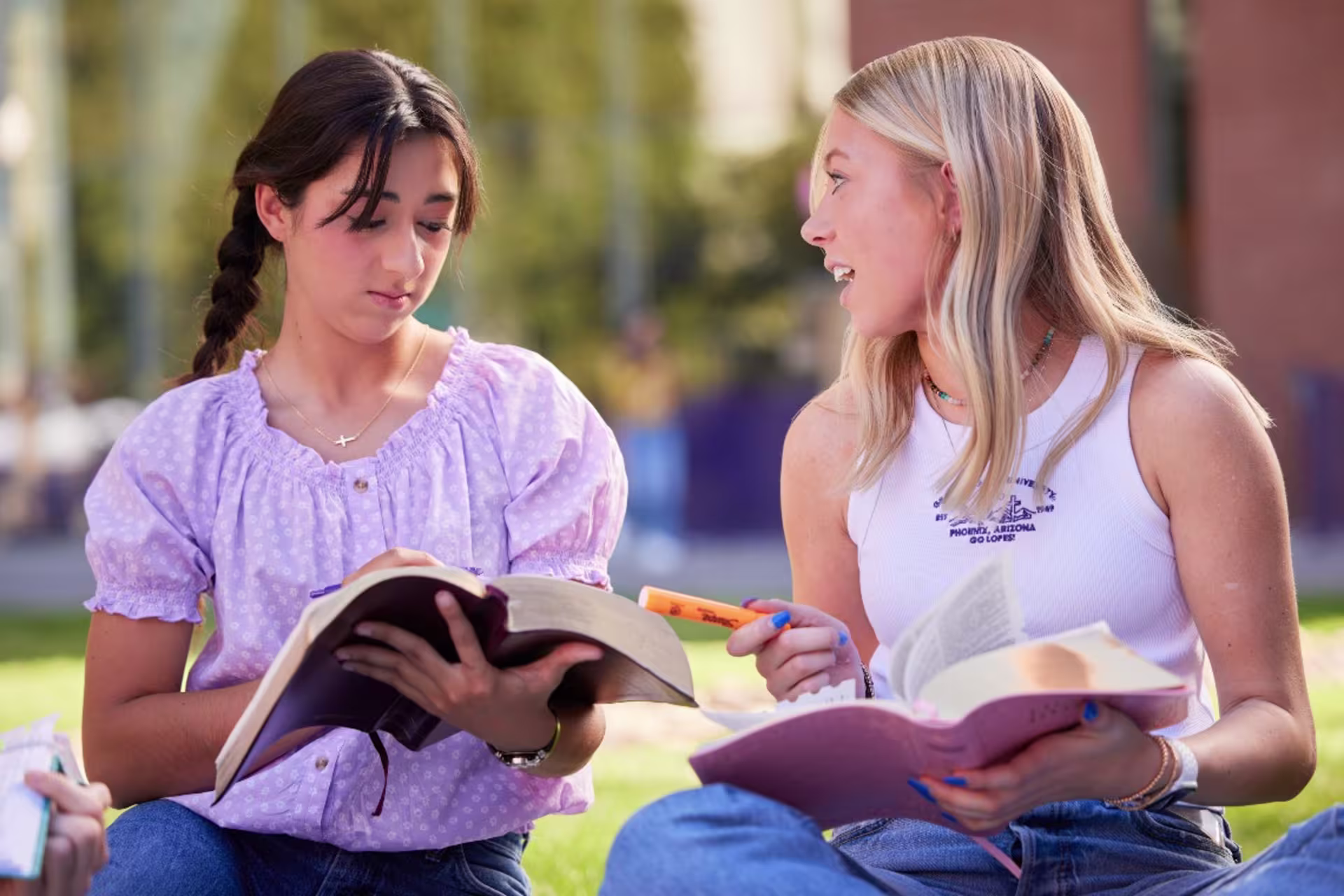 Two GCU students sitting outside discussing Christian studies with bibles in hand