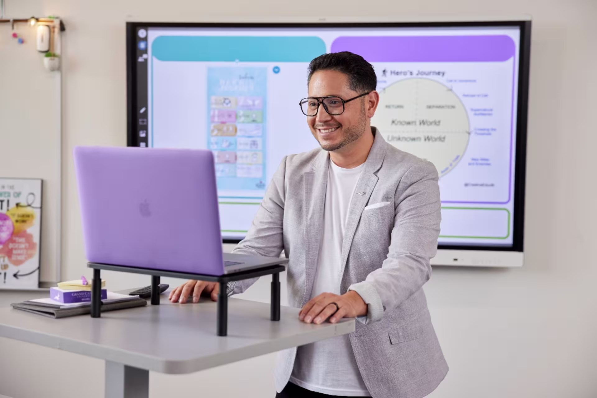 Data science student standing in front of presentation and working on laptop