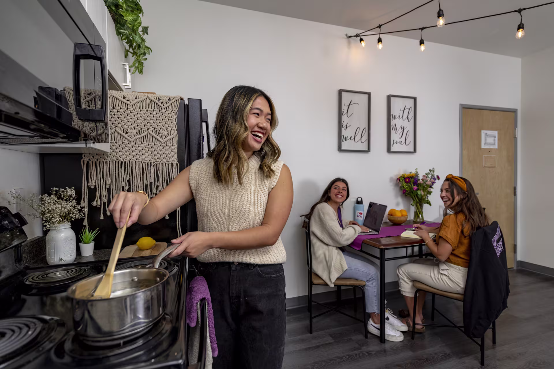 Group of female college students doing homework and cooking in apartment