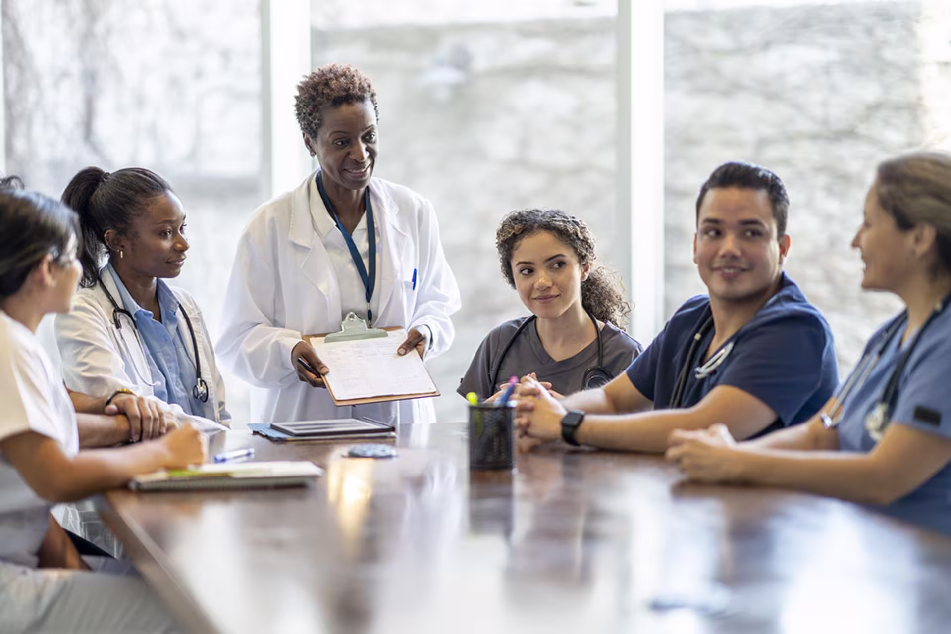 Group of health psychology professionals sitting at table in office collaborating and analyzing patient files