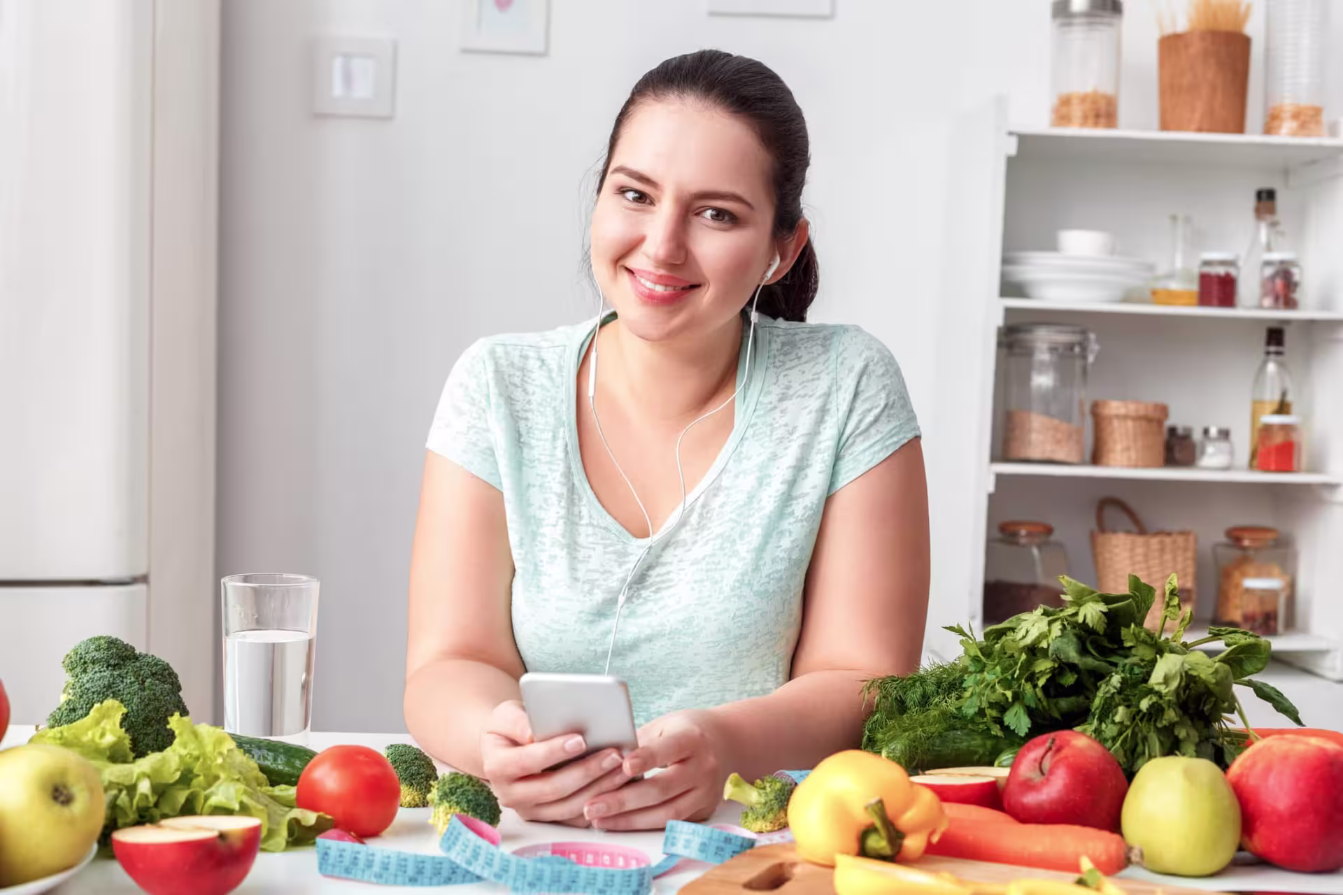 A nutritionist in the kitchen with an abundance of fruit and vegetables on the counter.