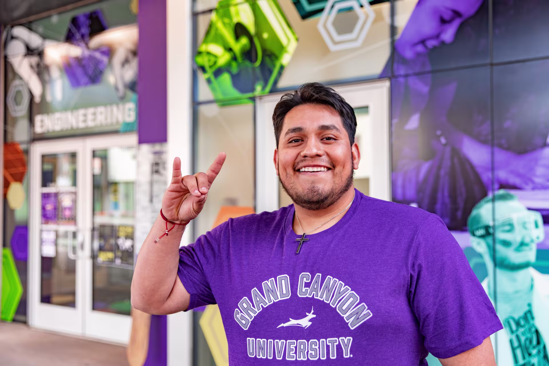 Male student smiling and throwing up lopes sign outside of GCU’s engineering college.