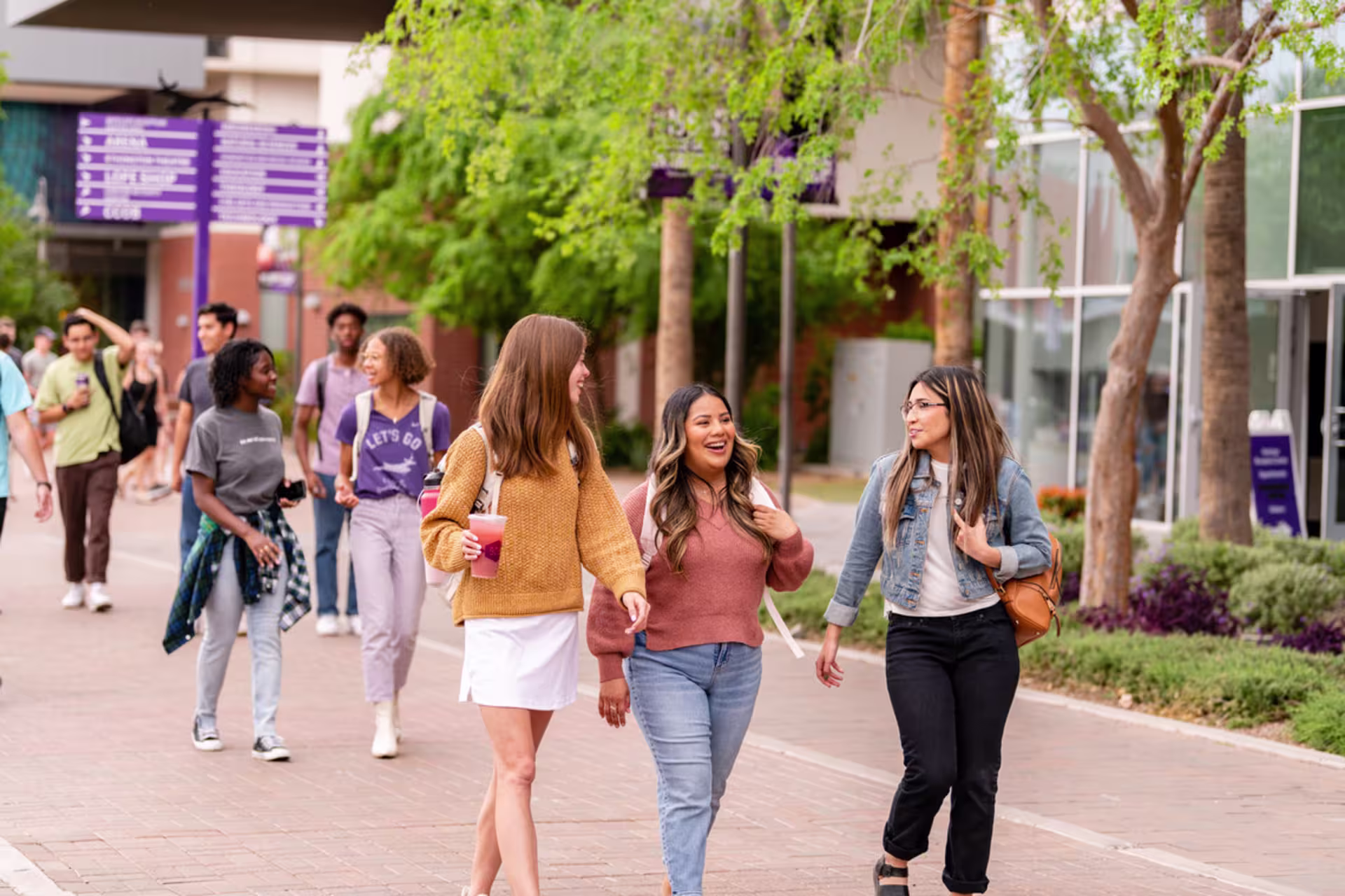 Group of female GCU students walking outside on campus while carrying their backpacks and books.