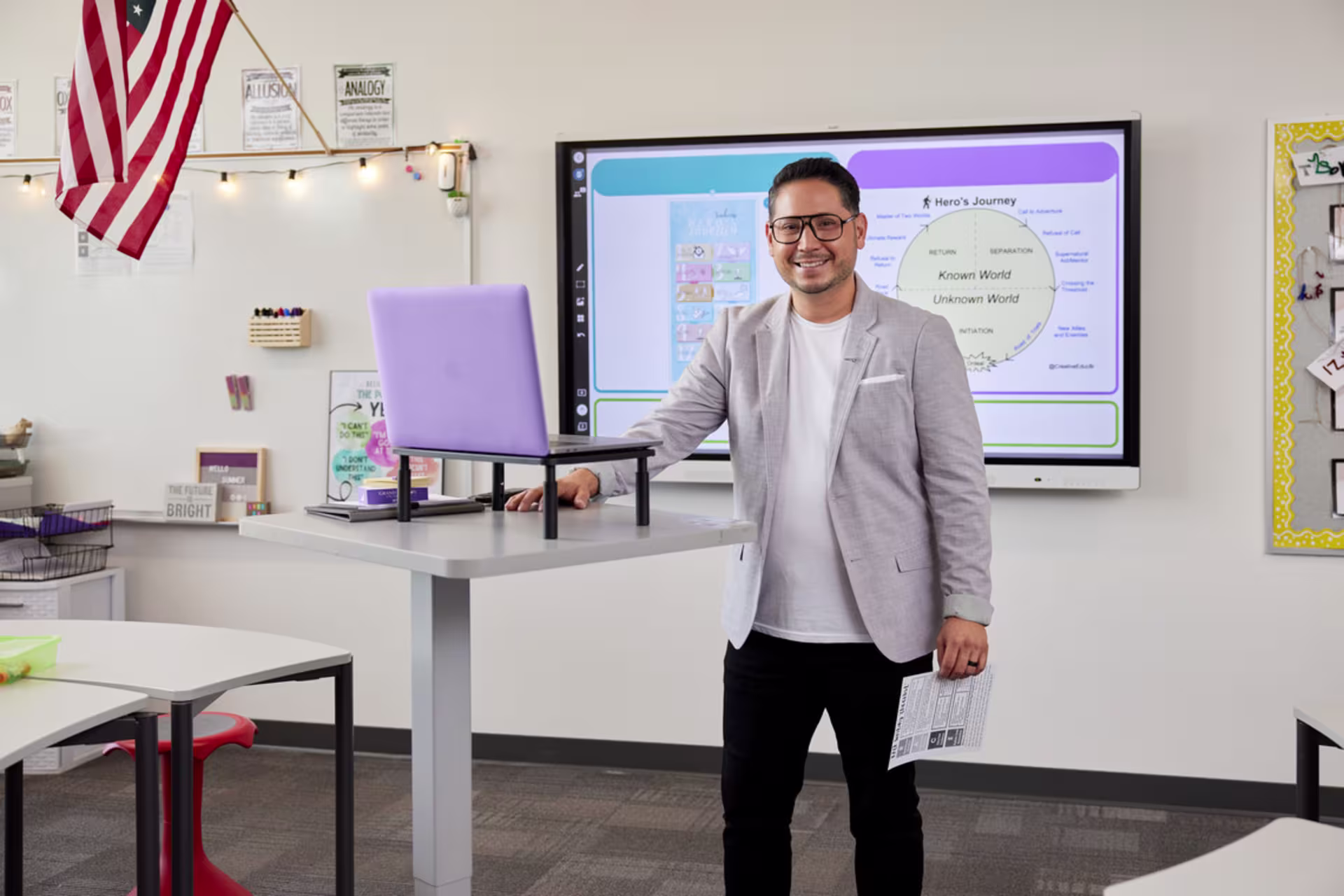 Teacher standing with a laptop at the front of a classroom