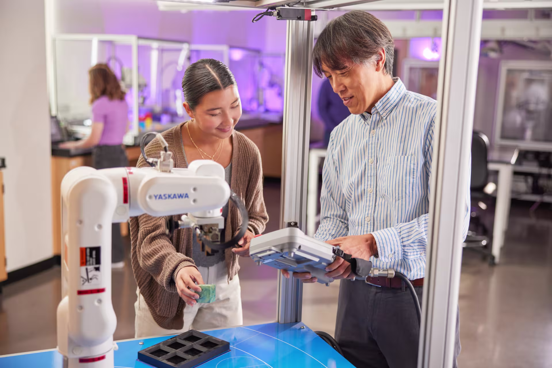 Female engineering major using 3D printer in classroom with male instructor