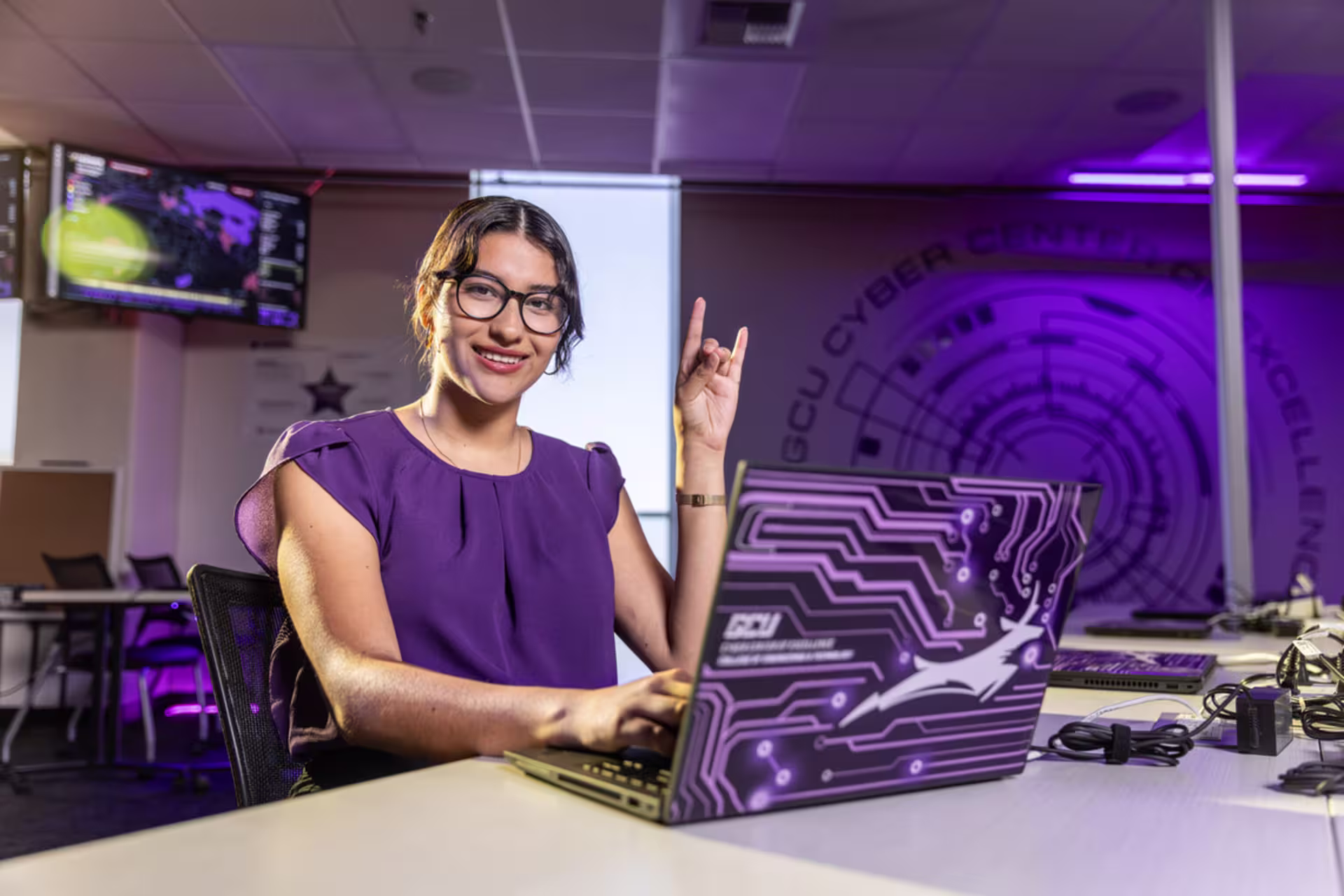 Female artificial intelligence student sitting at a desk and working on a laptop.