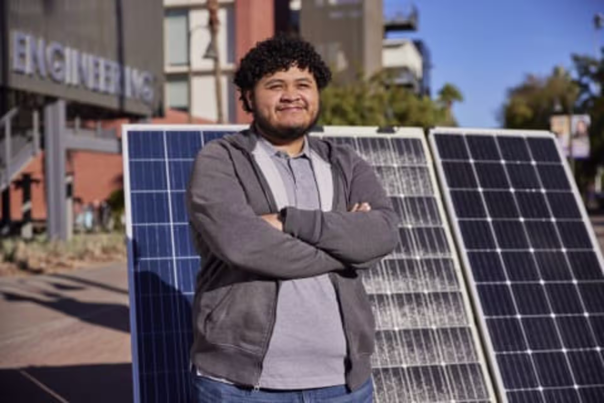 Male electrical engineering student outside posing in front of solar panels