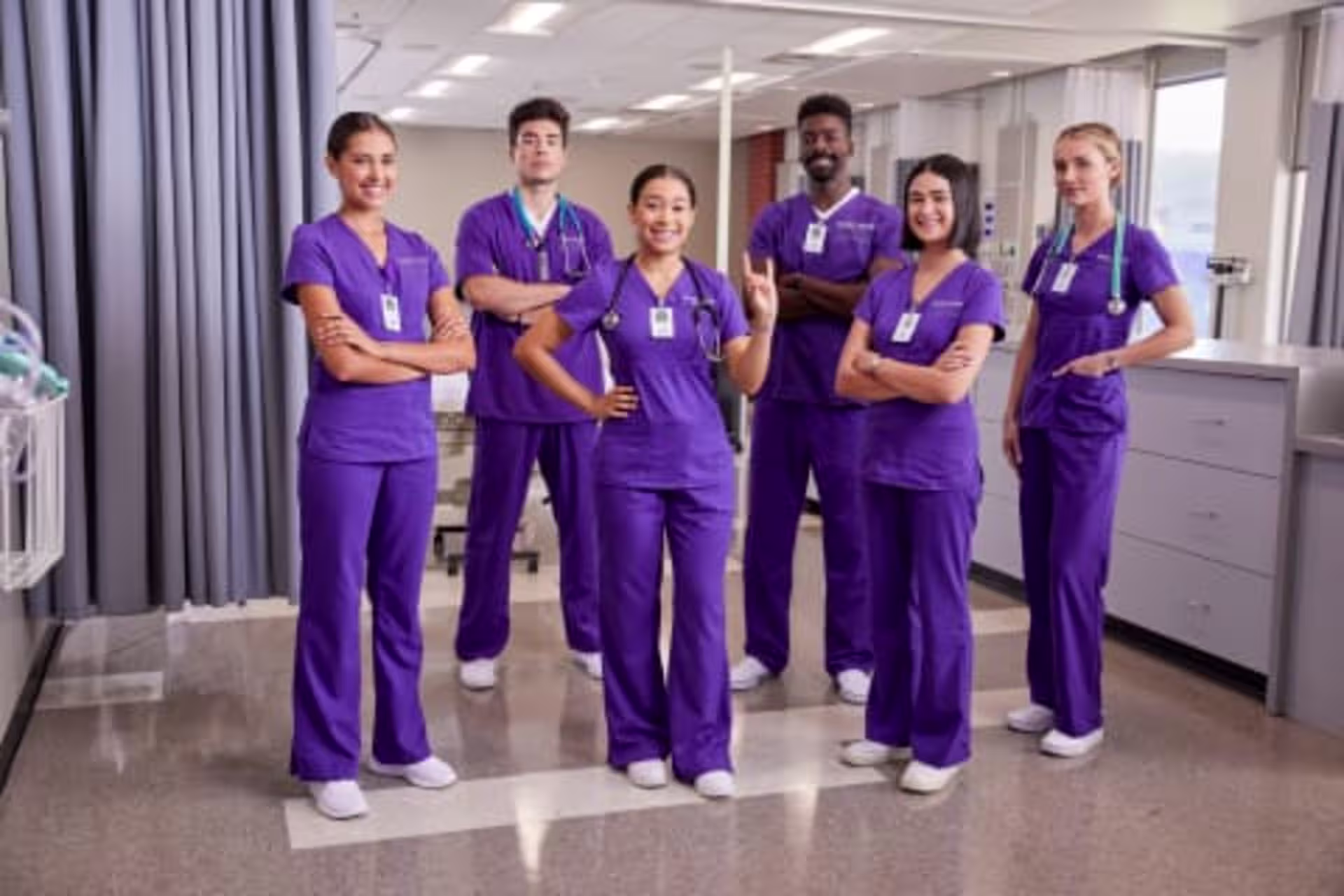 Group of ABSN students smiling and wearing scrubs in hospital