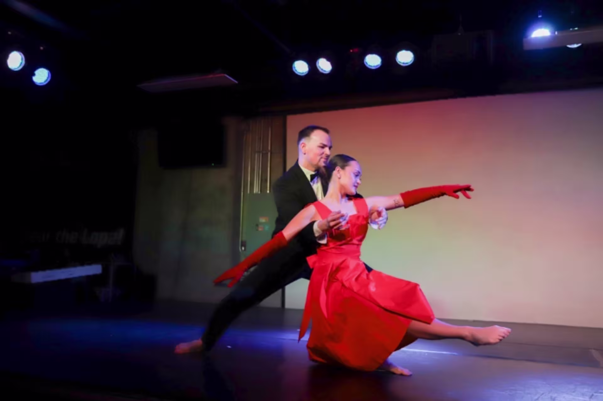 Male and female dancers twirling on stage in formal clothes