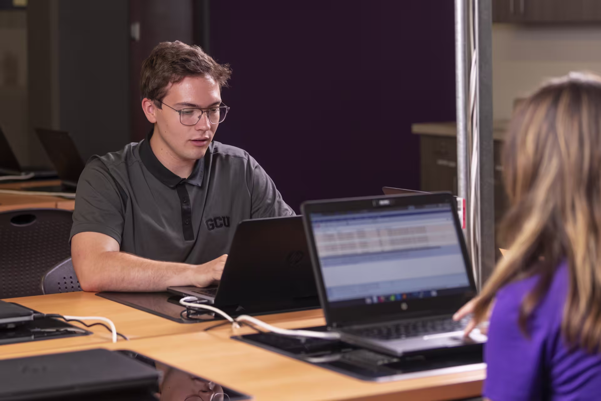 Two students working on open laptops as part of their online pre-master's in software development coursework.