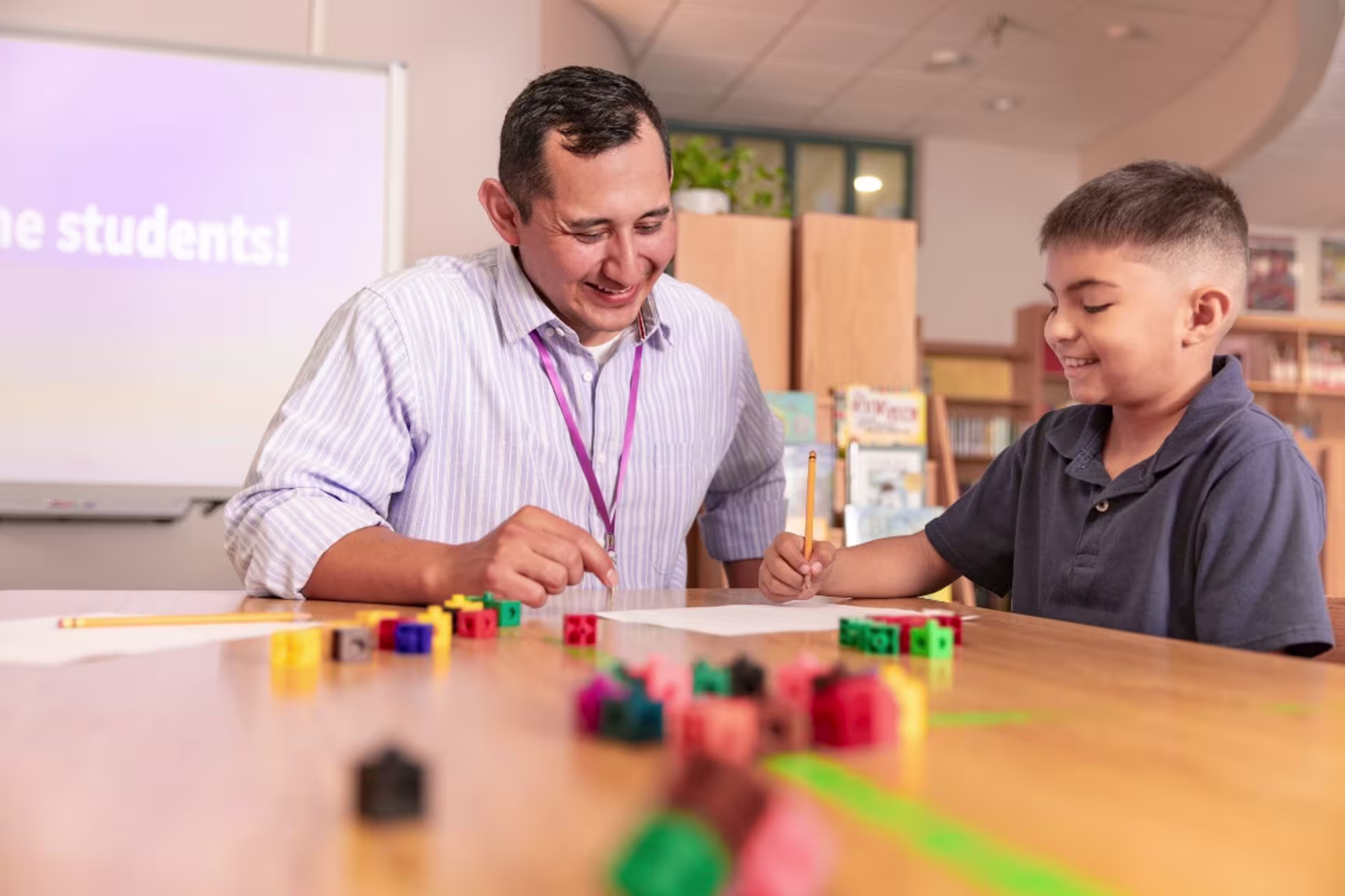 Man teacher playing blocks with young student in classroom environment