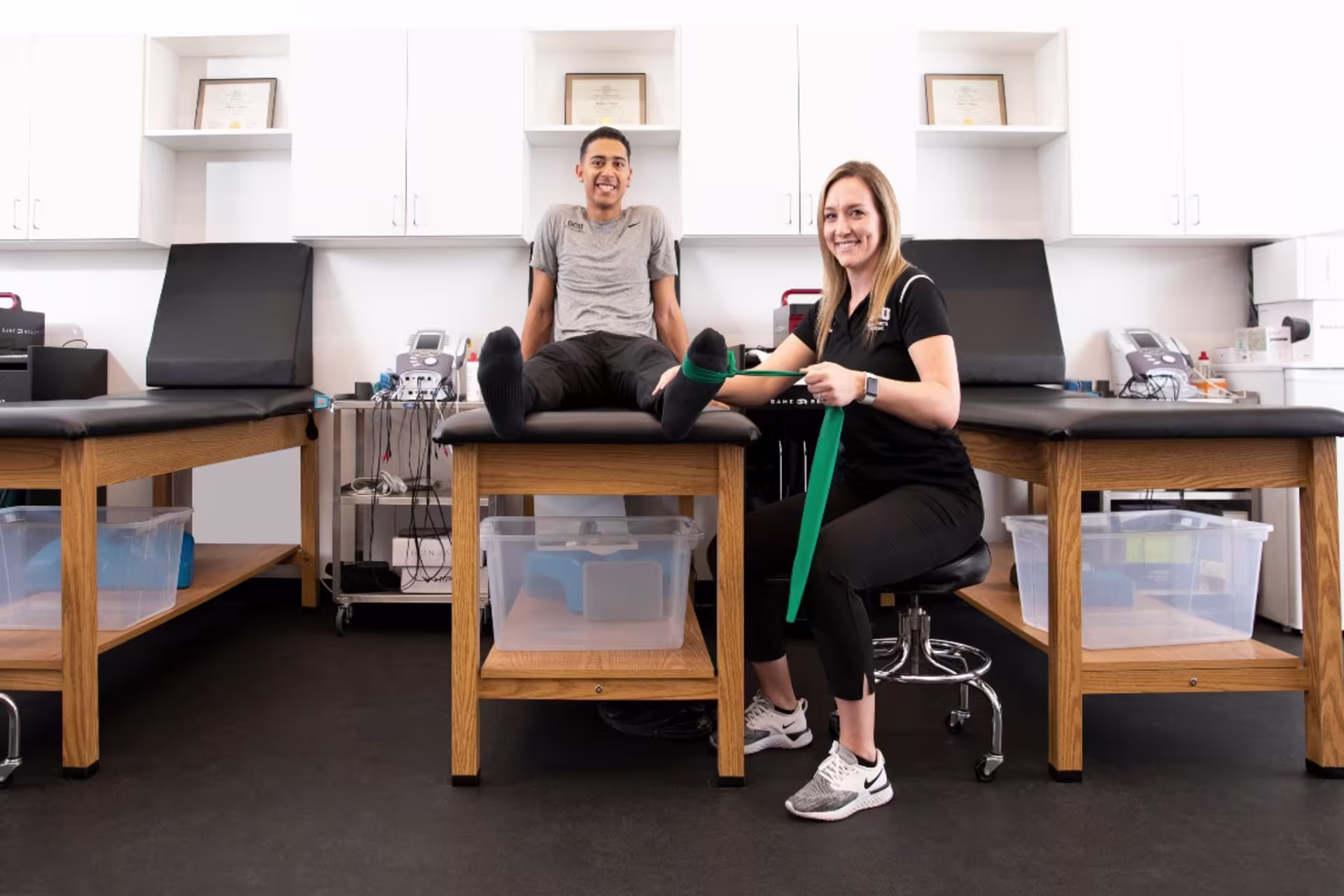 Athletic trainer in training room with student and bands