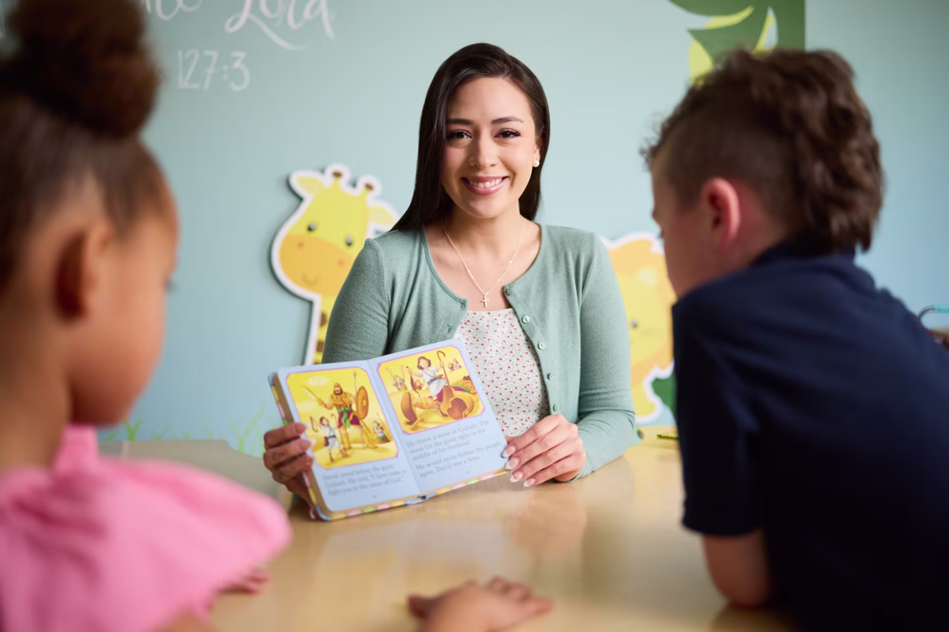 A teacher reading a children's book to young students, demonstrating early childhood education in a BS in Elementary Education: Teaching Reading degree program.