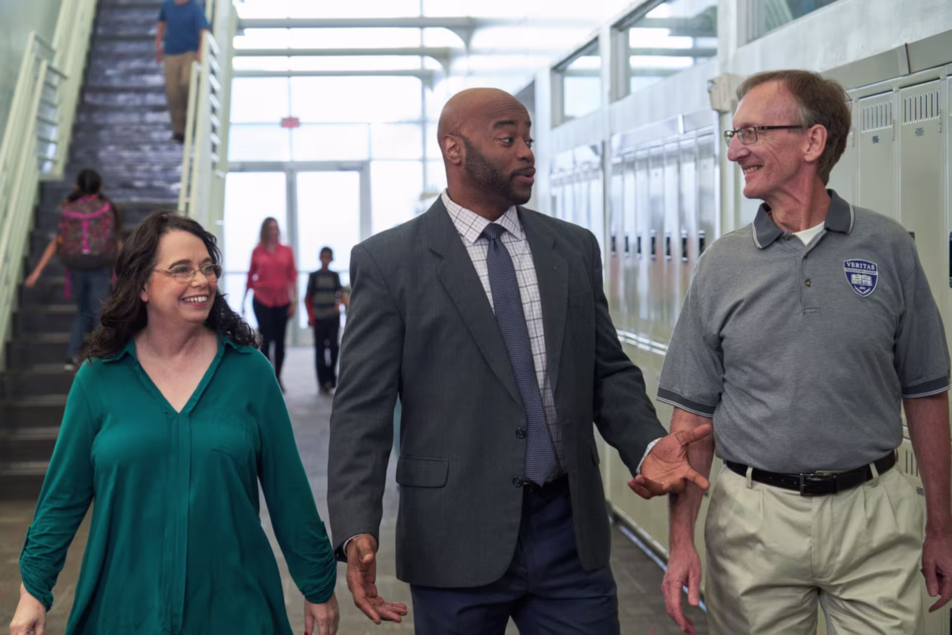Female and male organizational development professionals speaking to each other in school hallway