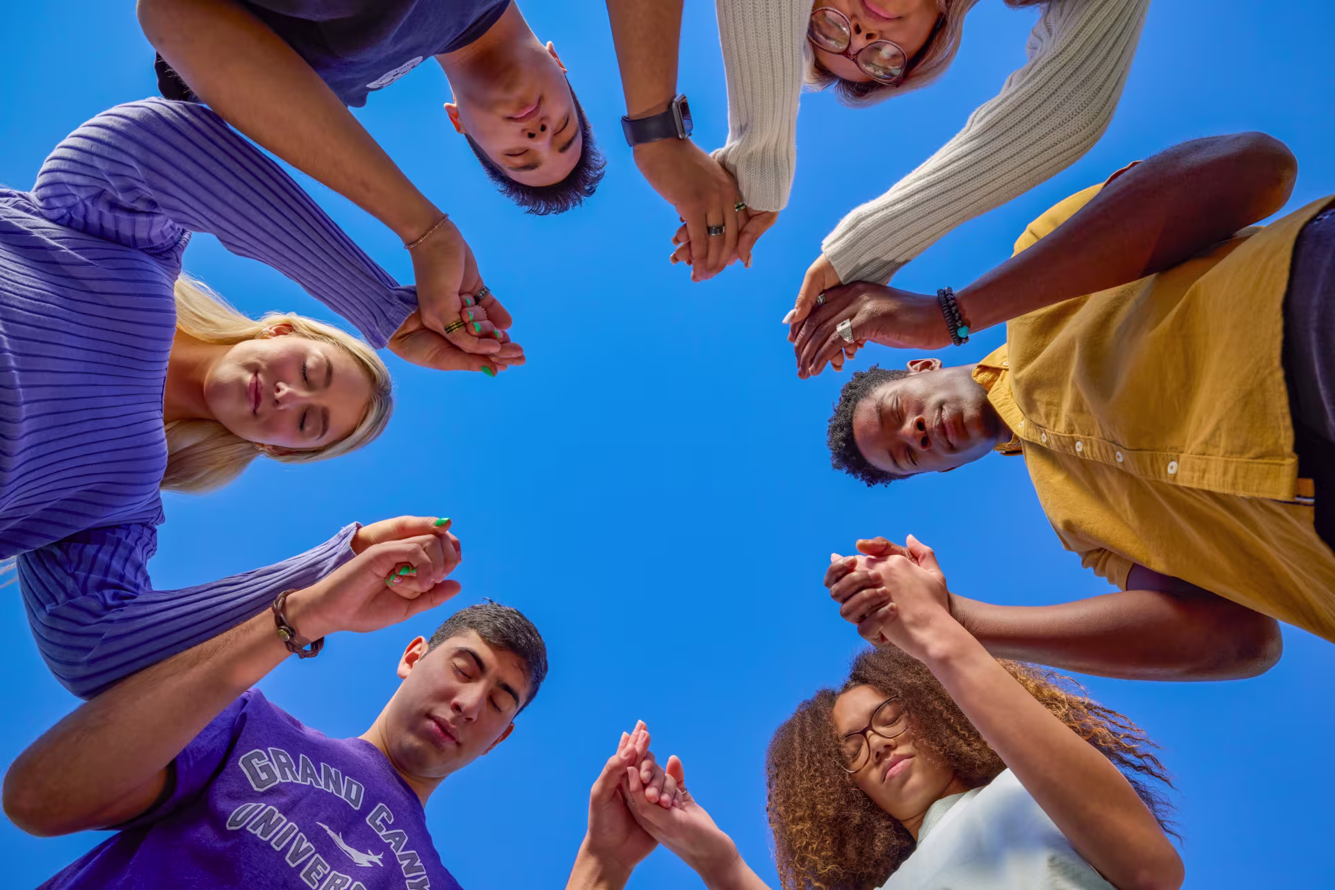 Group of male and female psychology majors standing in prayer circle