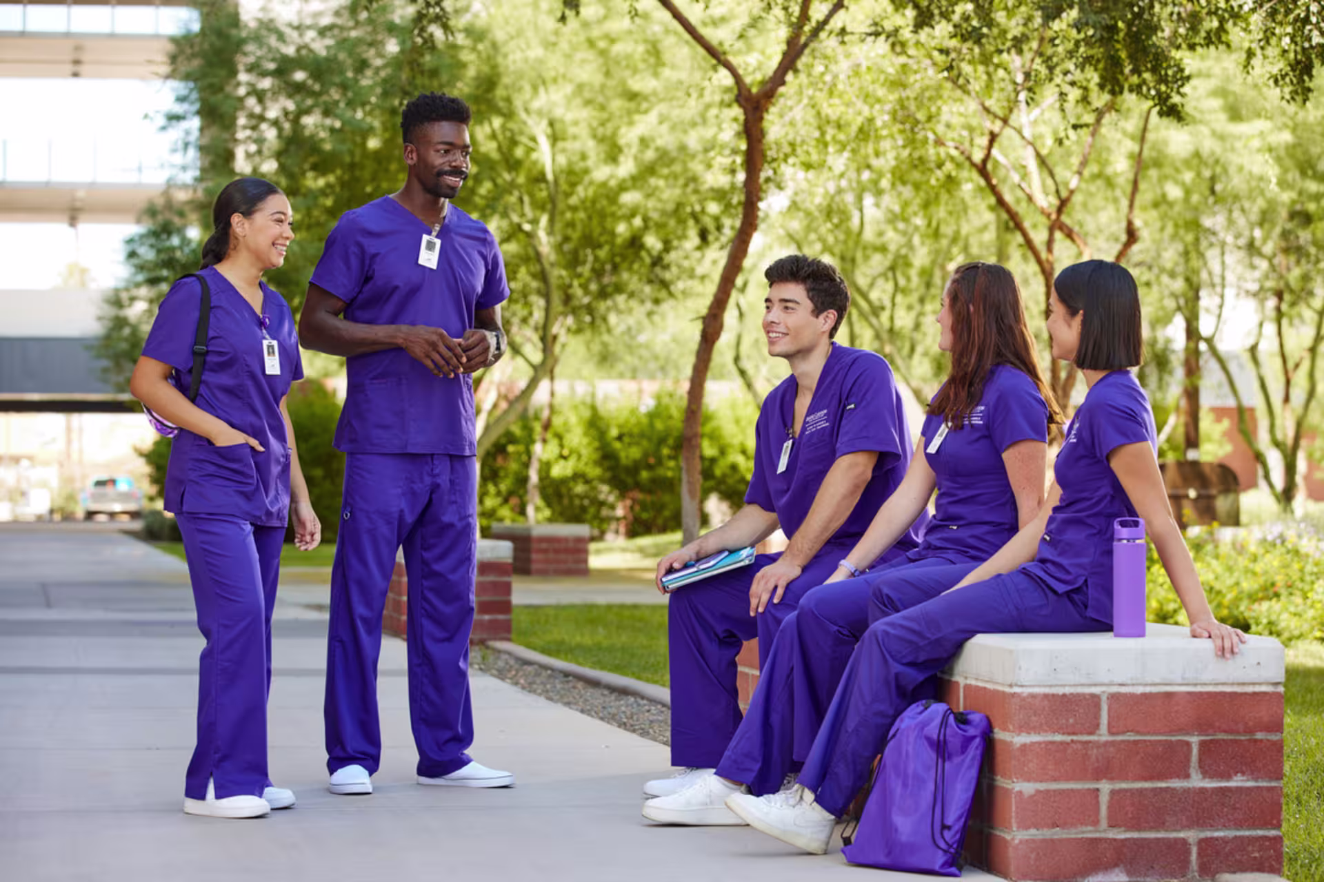 male and female nursing students talk sitting and standing outdoors