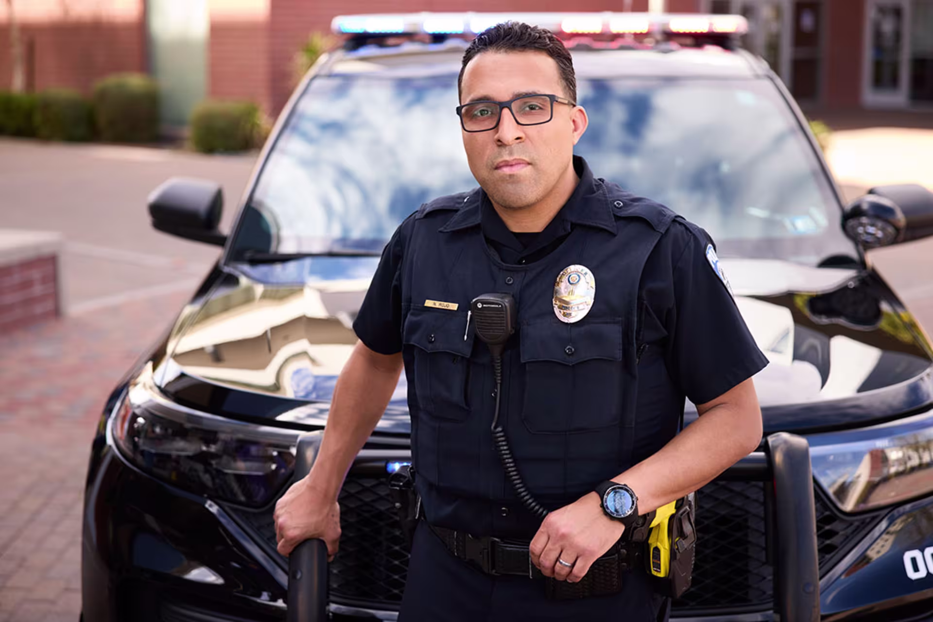 Male officer standing in front of squad car