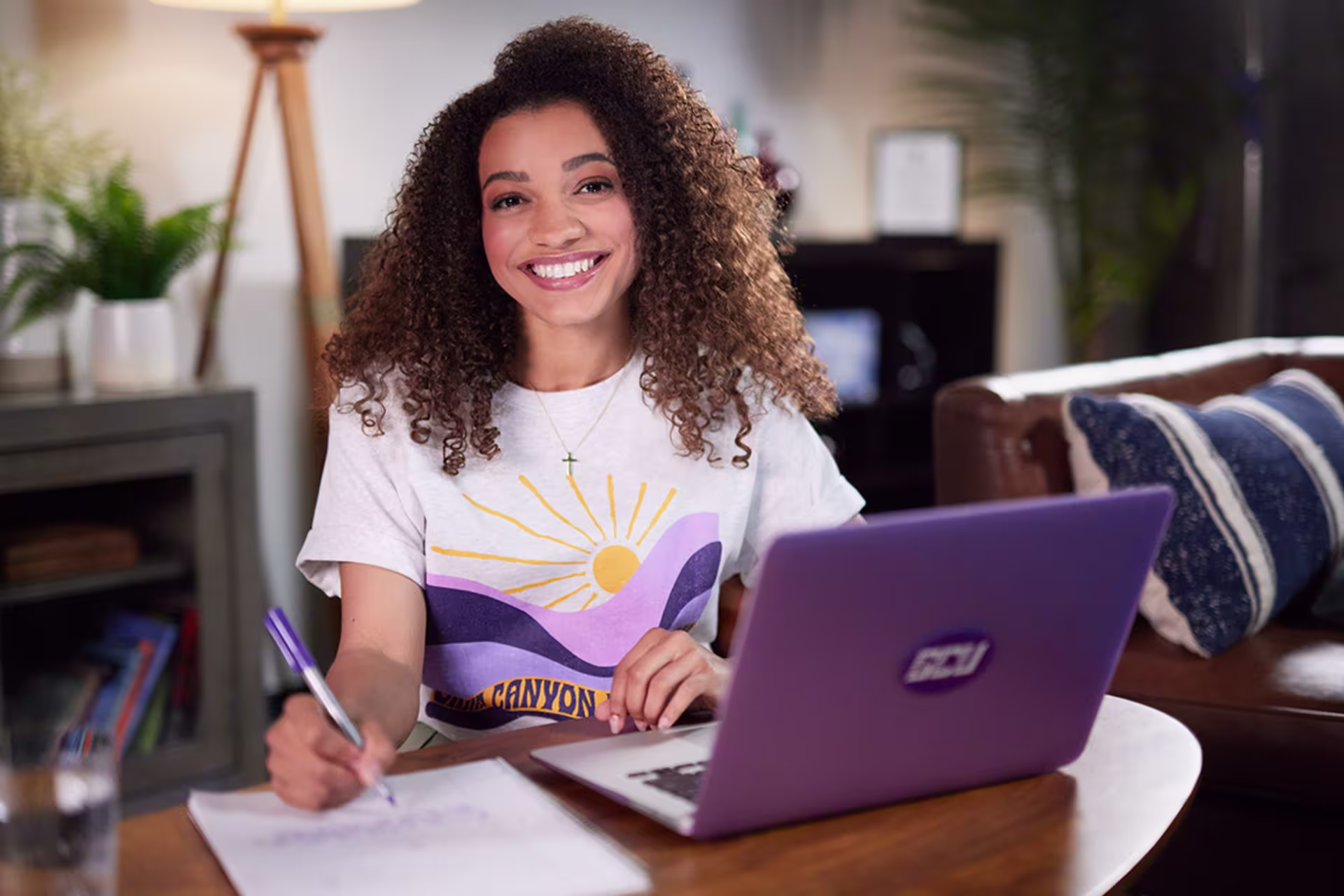 Online student sitting at a desk with a laptop and class notes