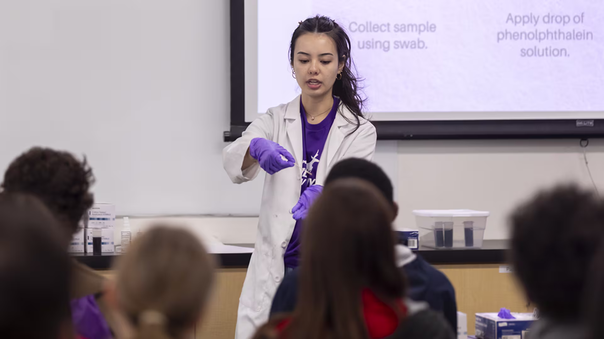 Female CNS student showcasing experiment in front of class