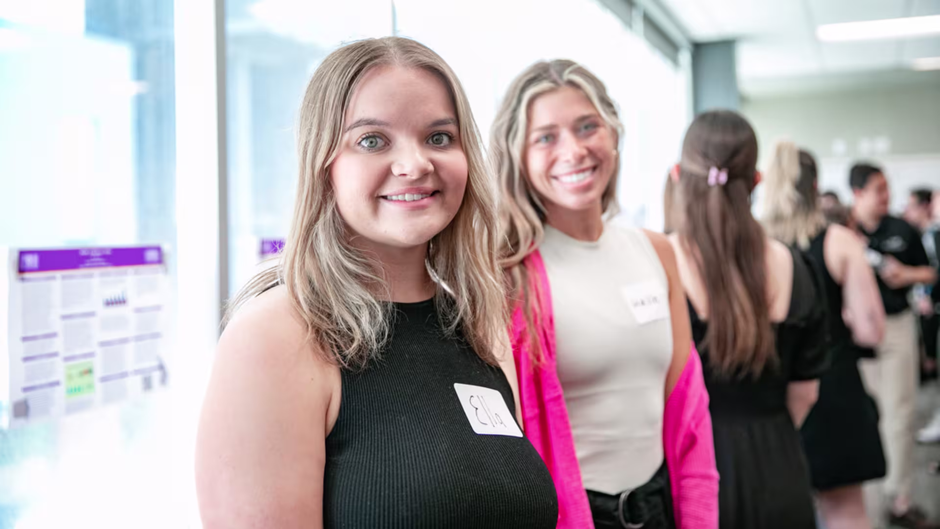 two blonde girls smile while waiting to present at student showcase