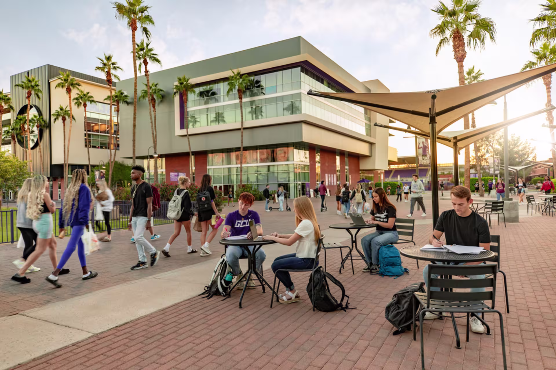 Student walking on campus and students siting at tables studying 