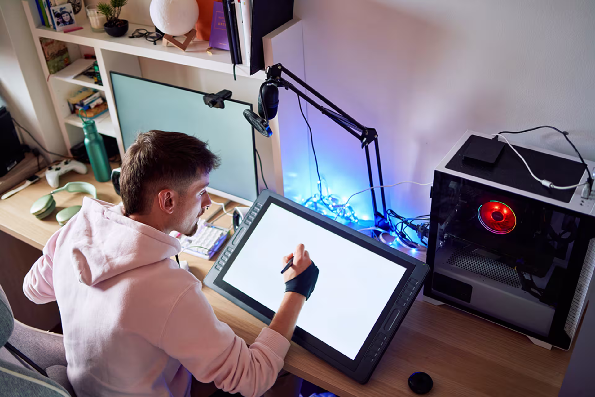 male digital design student uses design pad in dorm room at a desk with a full CPU set-up