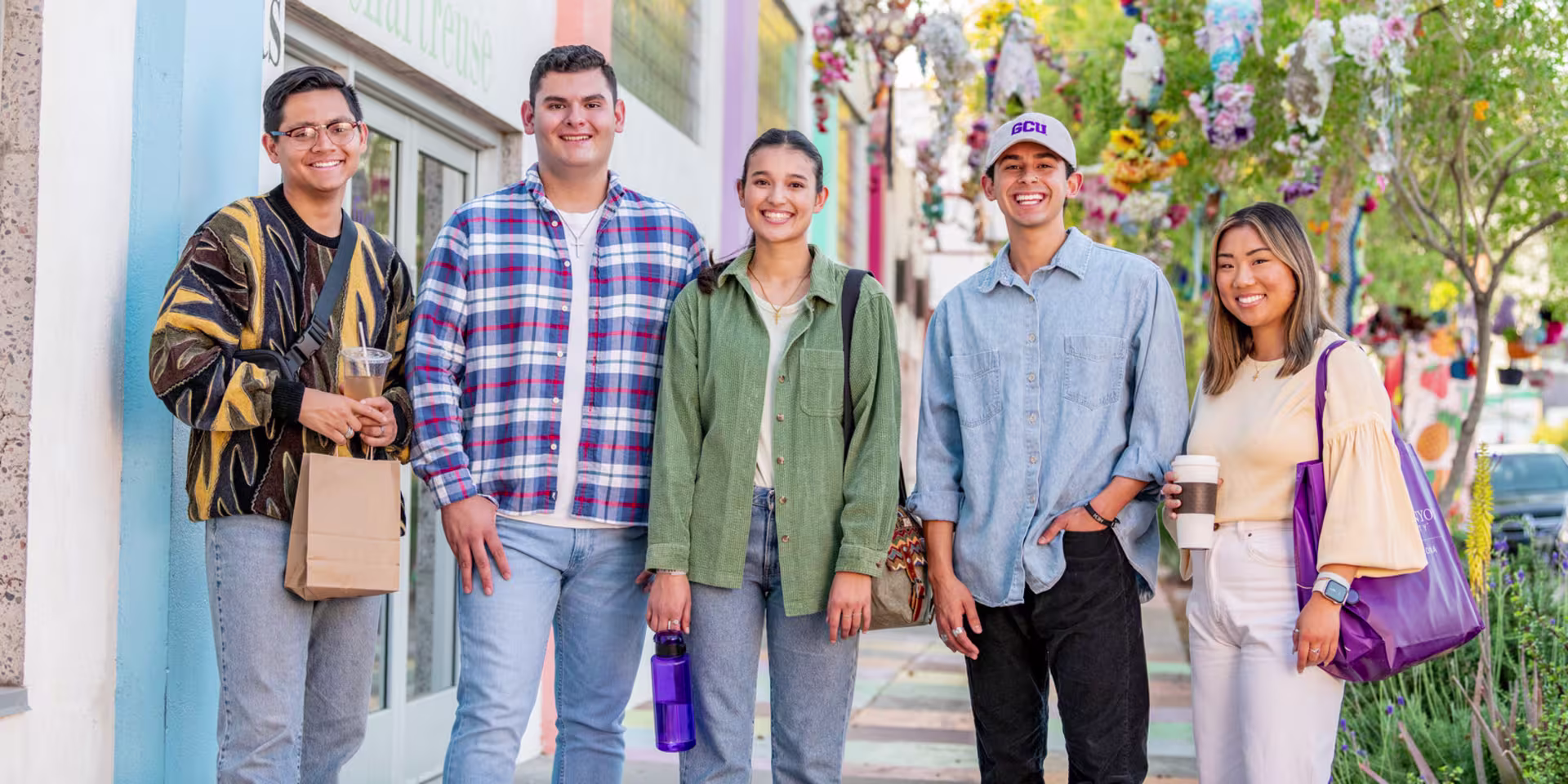 GCU students stand together in the street, all wearing casual clothes while smiling.