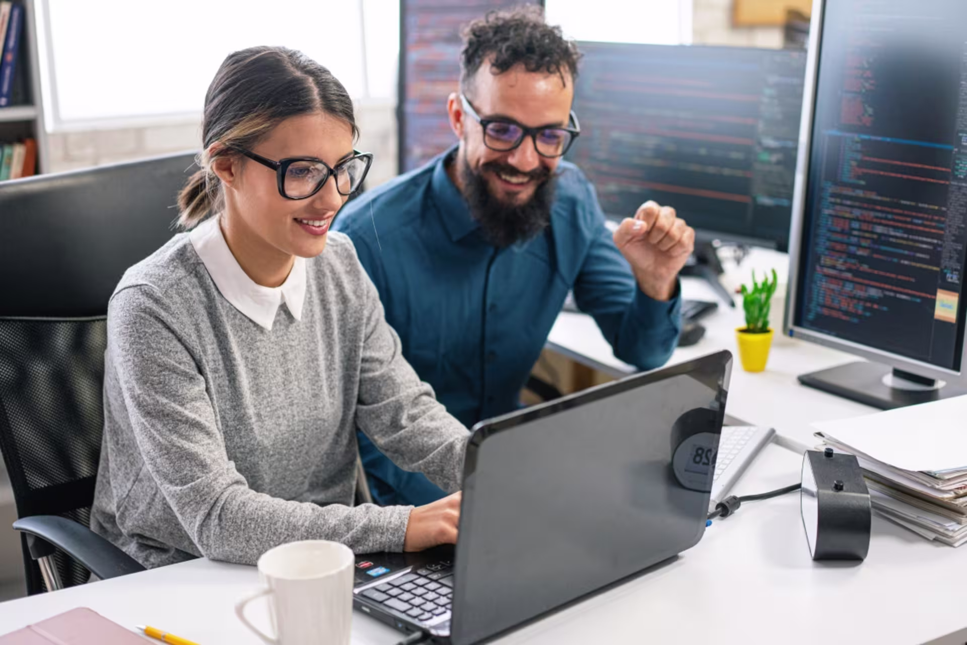 A male and a female data scientist collaborate while reviewing data on a computer.