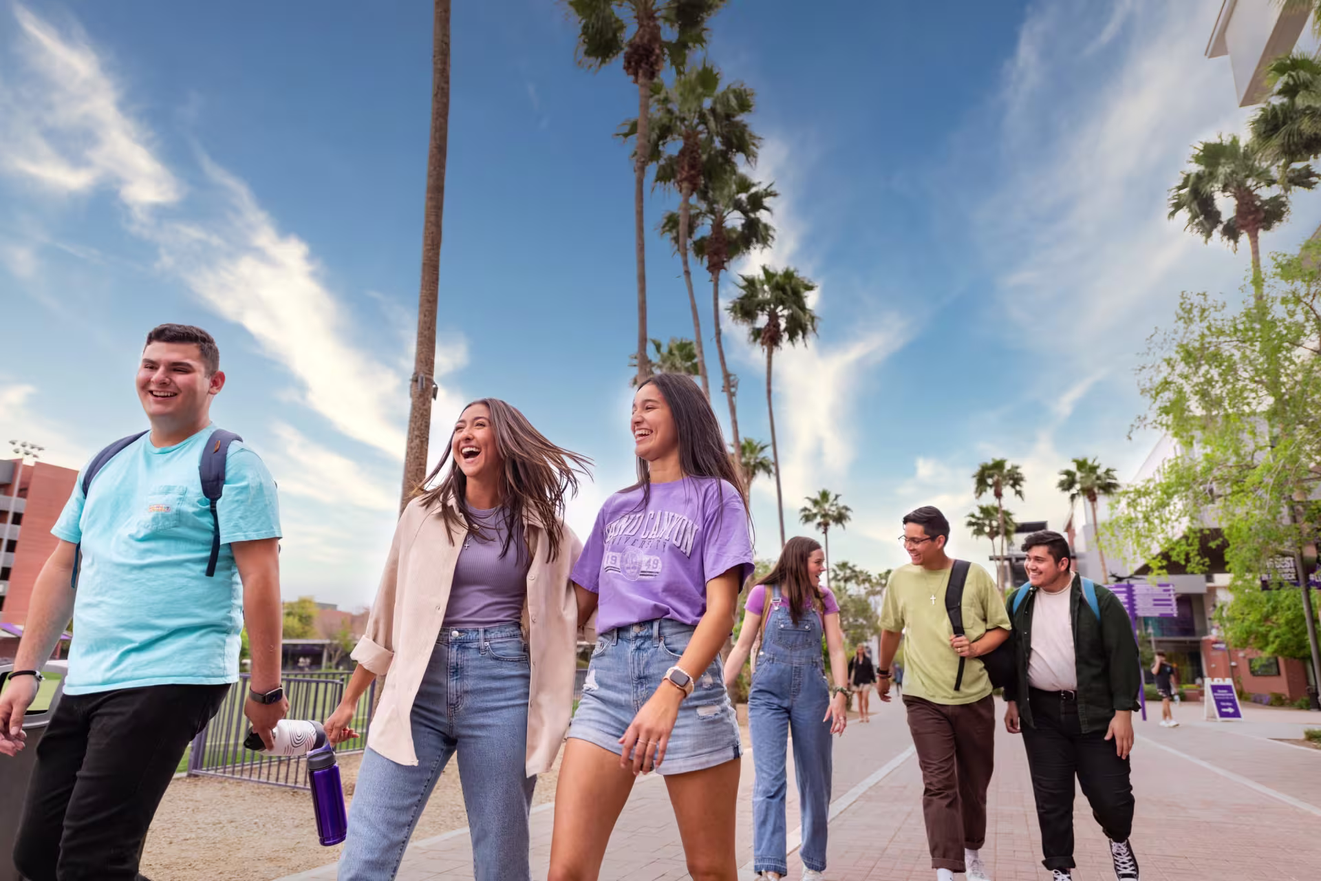 A group of students walking on campus smiling.