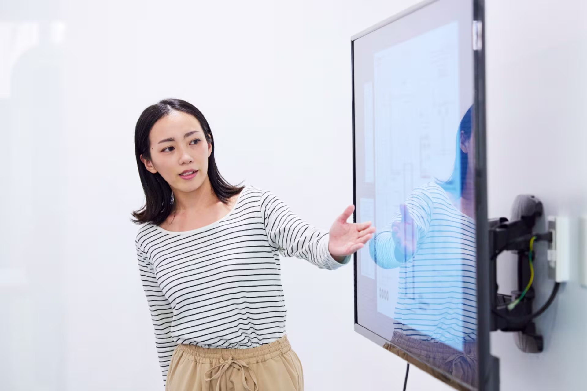 Female graduate instructional design student presenting design models on a large screen.