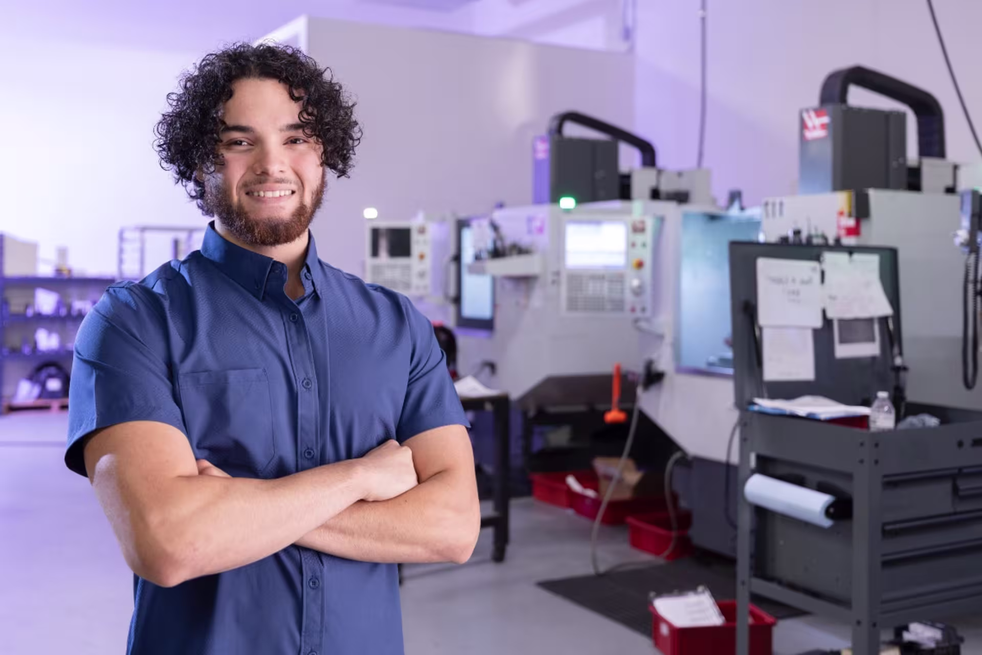 Male facilities engineering student standing in an engineering lab with industrial equipment in the background.