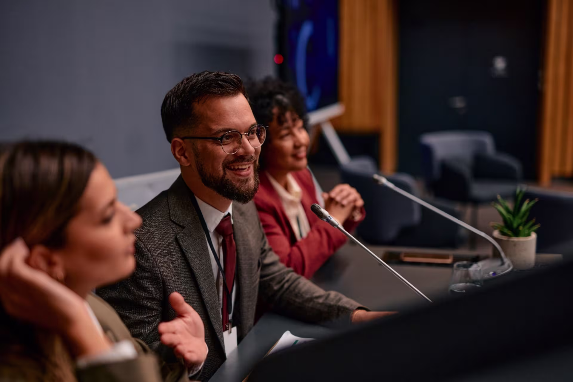 Group of politicians sitting together, gesturing animatedly while speaking into microphones during an engaging press conference, sharing insights and opinions on important issues.