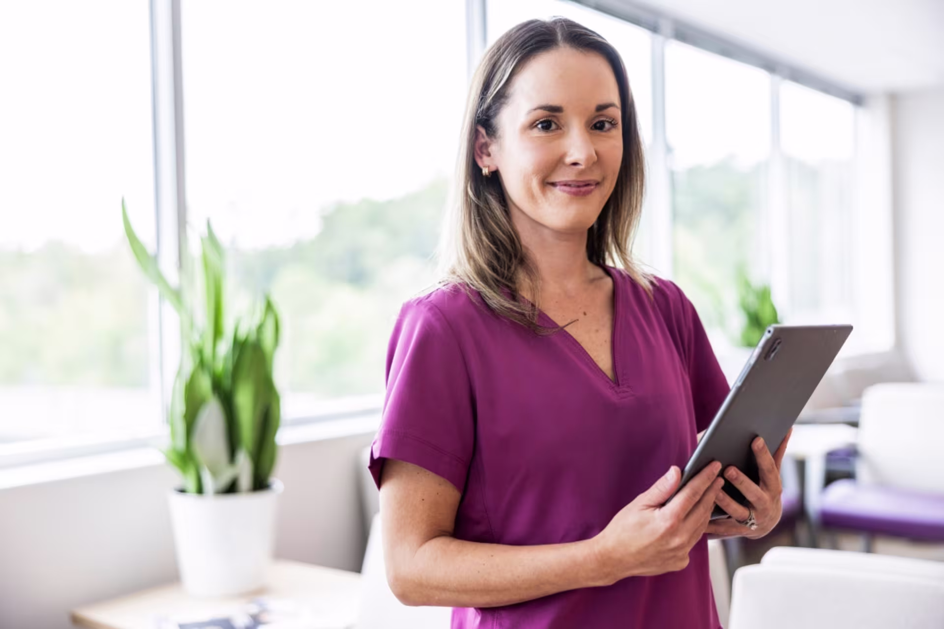 A female MSN: public health nursing graduate stands in a hospital and holds patient charts. 