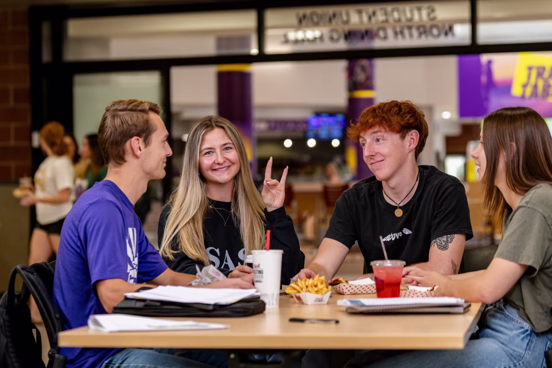 GCU students eating and talking together inside the Student Union North dining hall in a relaxed, social campus setting.