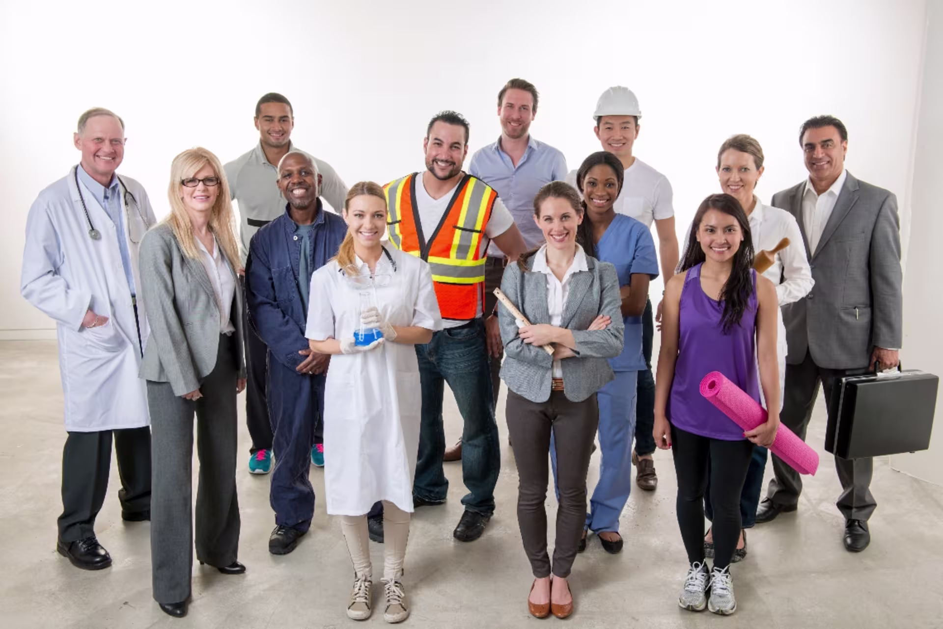 Diverse working professionals from different career paths, including healthcare, construction, business and skilled trades, standing together in a simple room with a white background.