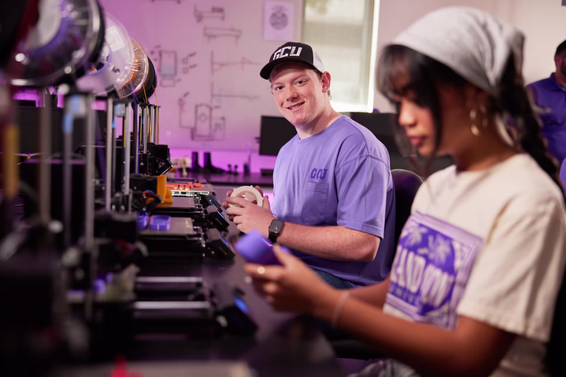 Engineering students testing 3D-printed prototypes in a fabrication lab.