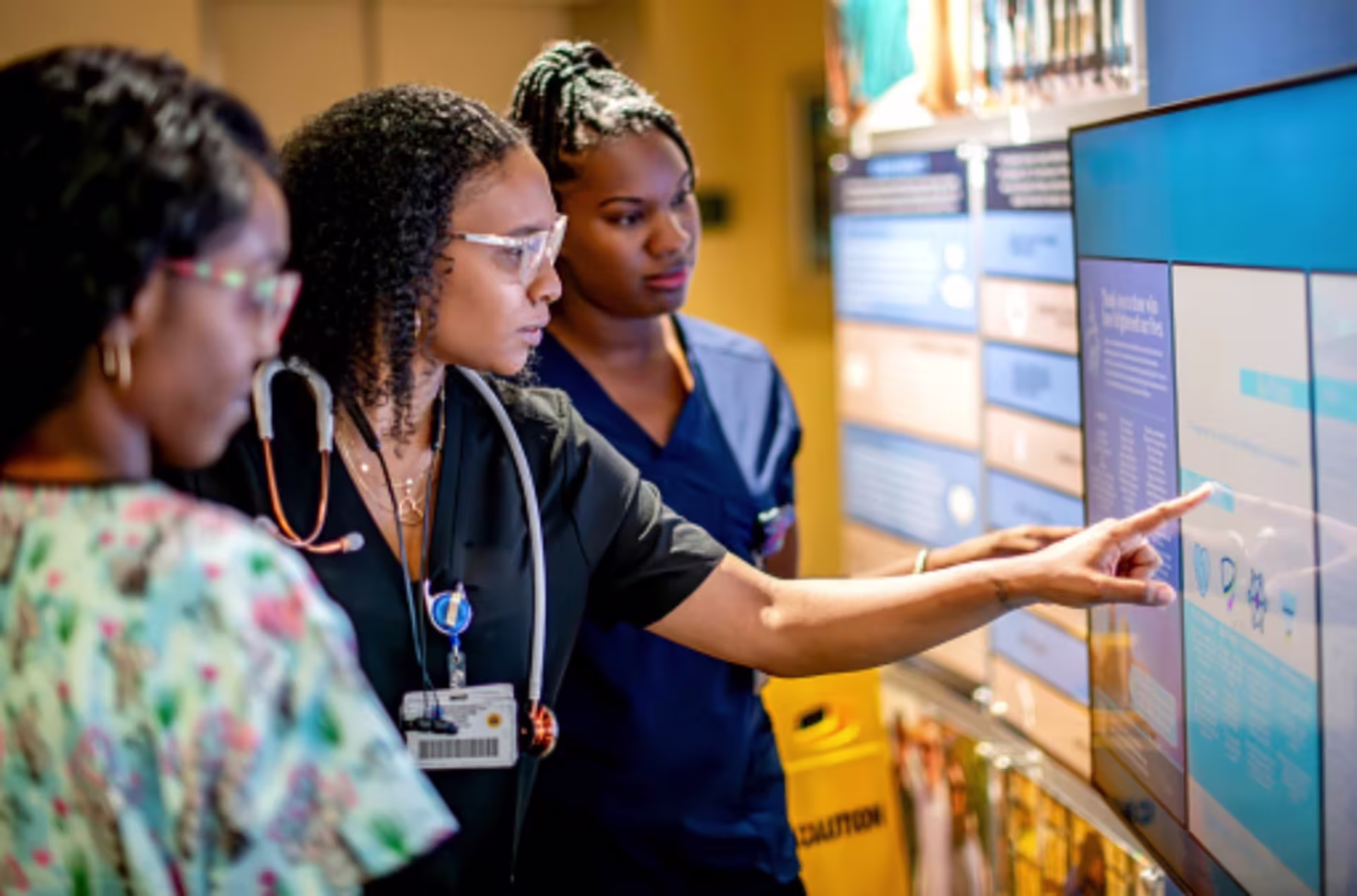 MSN: Nursing students review patient care information on a digital display during a clinical training session in a healthcare setting.