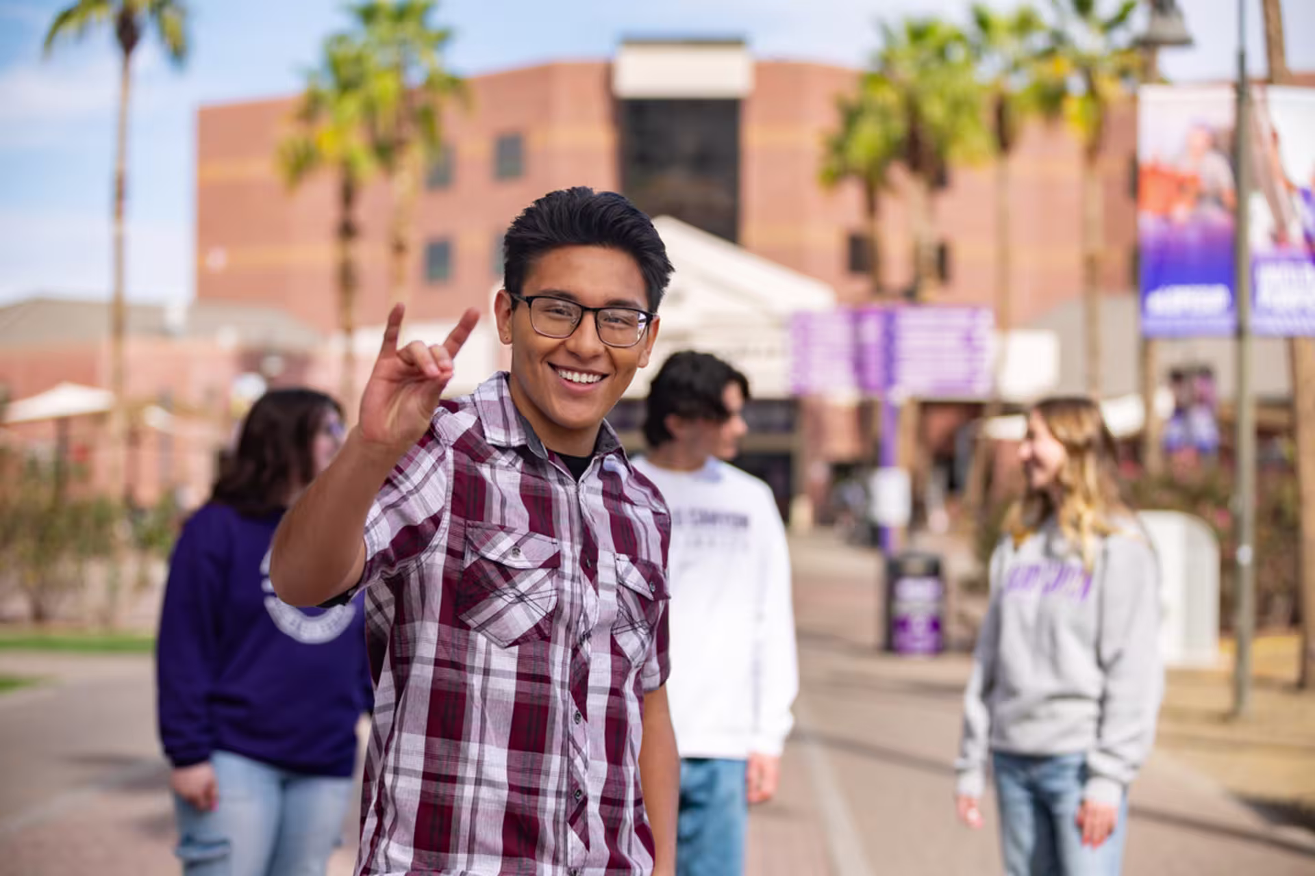 A male student holds up the Lopes Up hand sign while enjoying campus life.